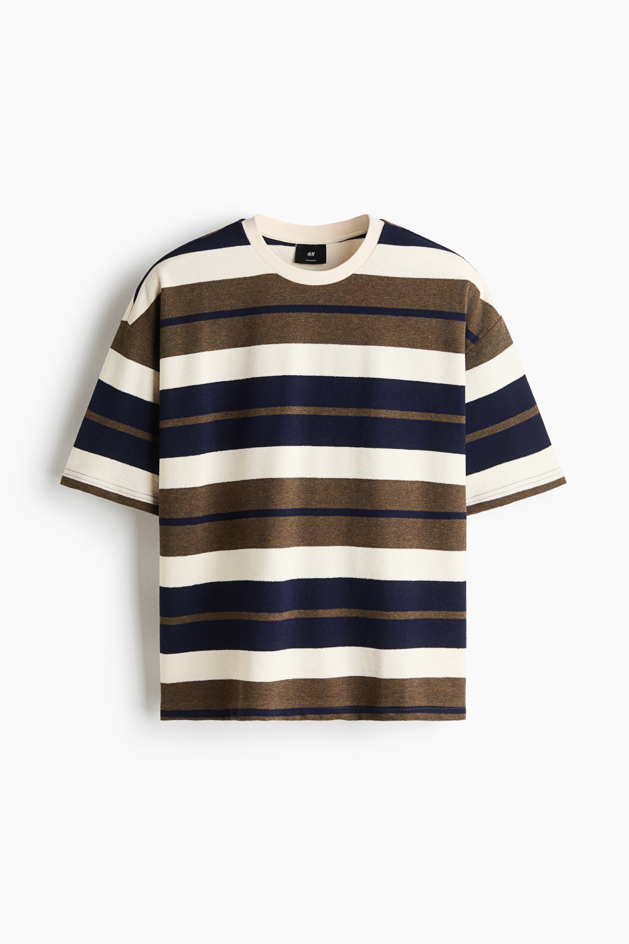Ver imagen más grande: Una camiseta muestra su parte delantera, con rayas horizontales en crema, marrón oscuro y azul marino. Presenta un cuello redondo con acabado de canalé, hombros caídos y un bajo de corte recto, creando una silueta oversize y holgada.