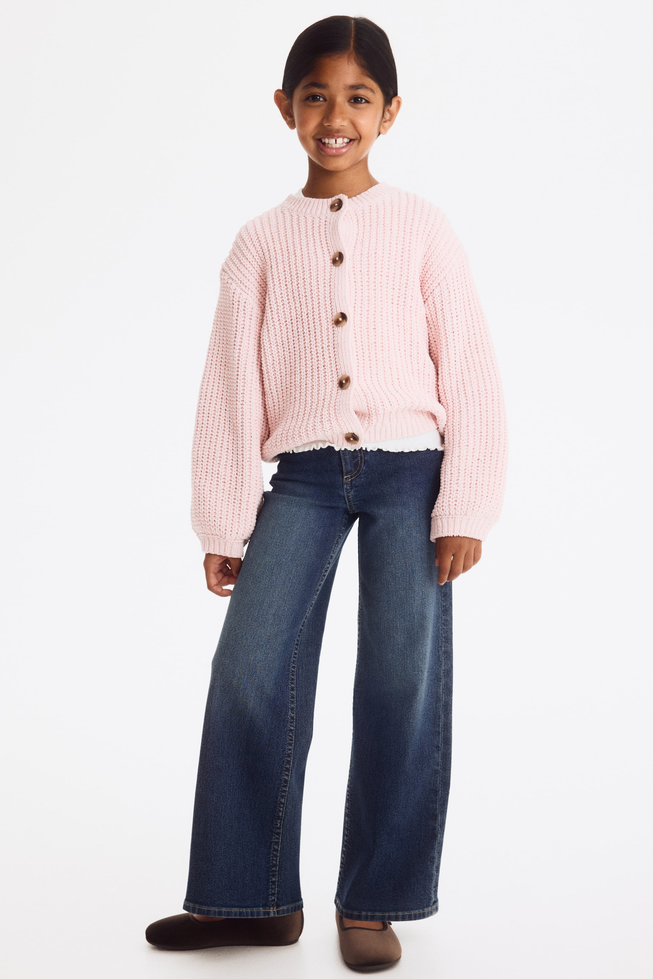 Xem ảnh lớn hơn: Quần jeans có tông wash denim xanh đậm, ôm gọn từ hông đến đùi, sau đó loe rộng xuống ống quần, với phần cạp trước có khóa cài nút và khóa kéo.