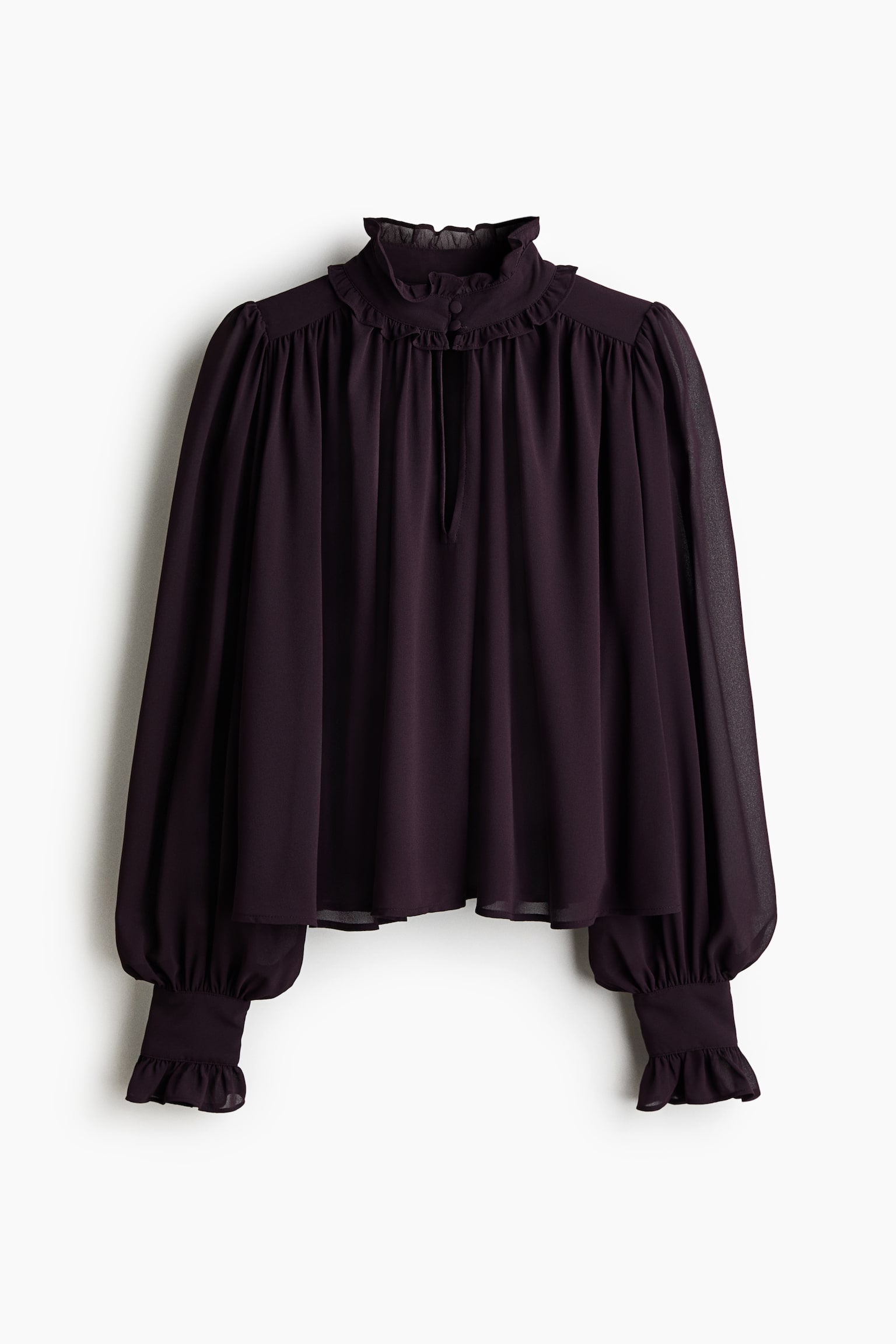 La blouse violet foncé est présentée de face, avec un col montant à volants doté d'une petite fermeture à bouton et d'un détail noué. Elle arbore des manches longues et volumineuses resserrées aux poignets à volants et un corps ample en tissu transparent. - 1