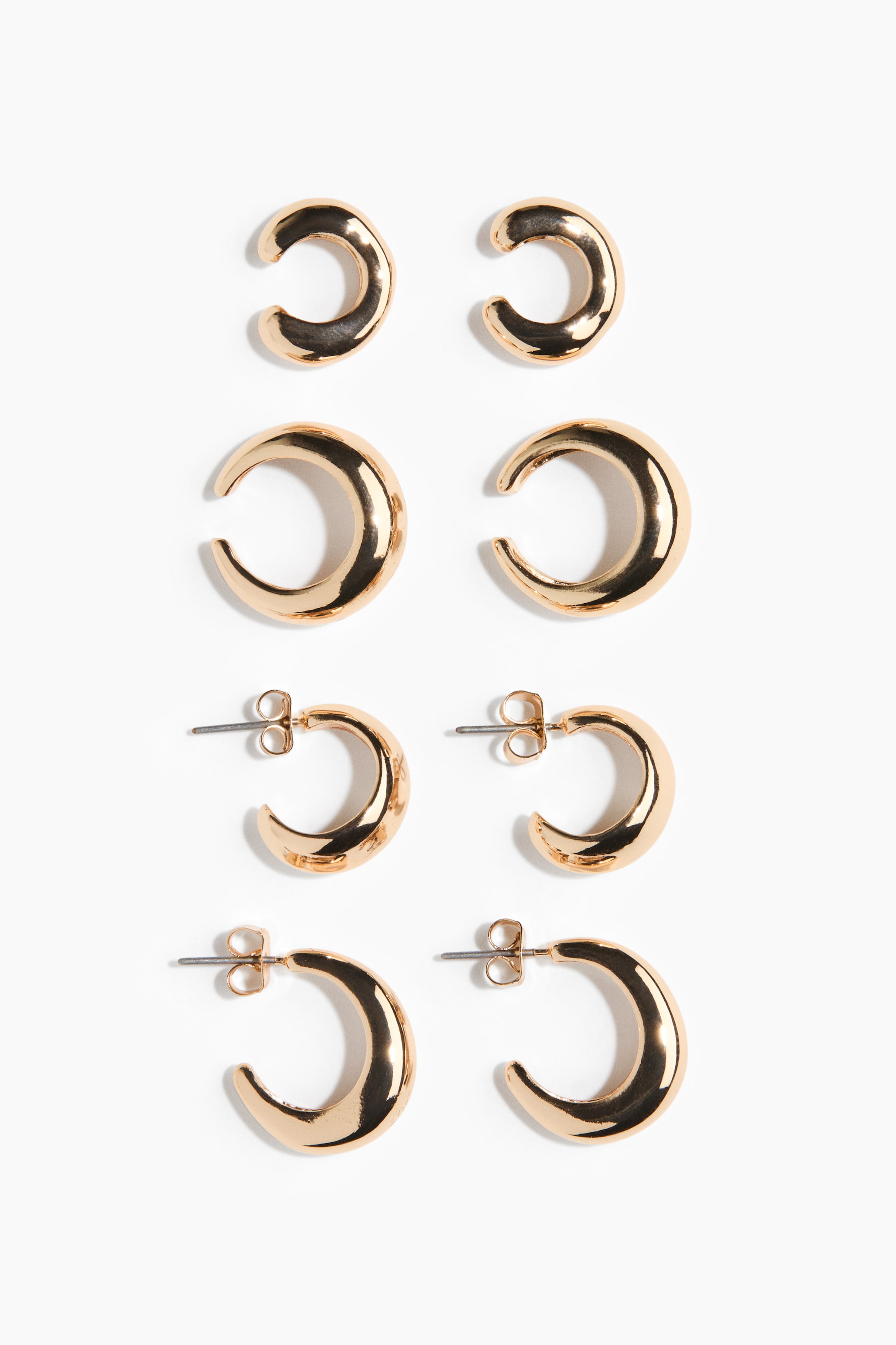 View larger image: A set of four pairs of gold-toned earrings displays a vertical arrangement of polished crescent-shaped designs. The top two pairs feature open-ended ear cuffs in small and medium sizes, while the bottom two pairs show hoop earrings with post-back closures and butterfly backings.