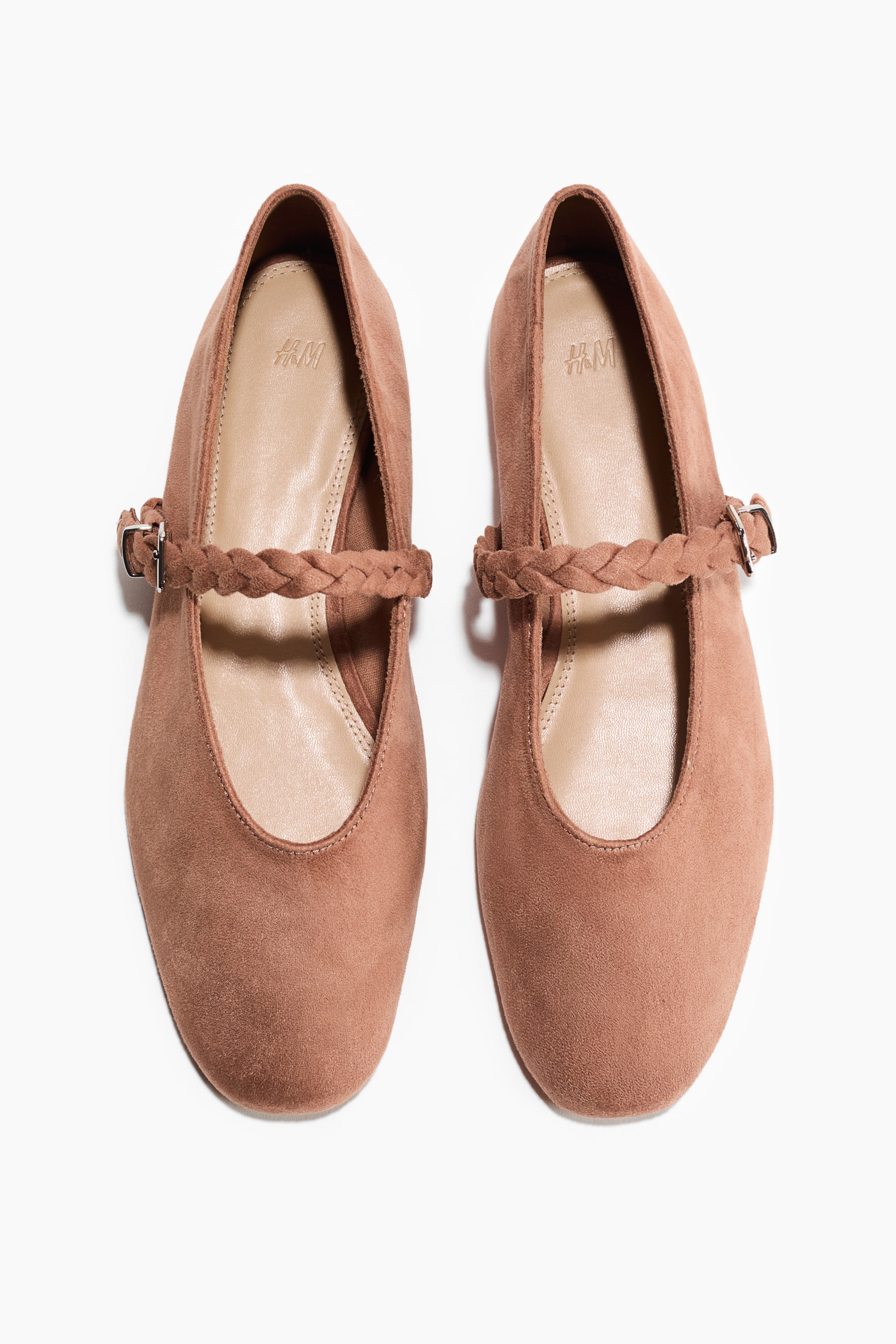 View larger image: Front-facing Mary Jane ballet flats showcase a light brown, soft, napped finish with rounded toes. An adjustable braided strap extends across the foot, secured by a silver-toned buckle.
