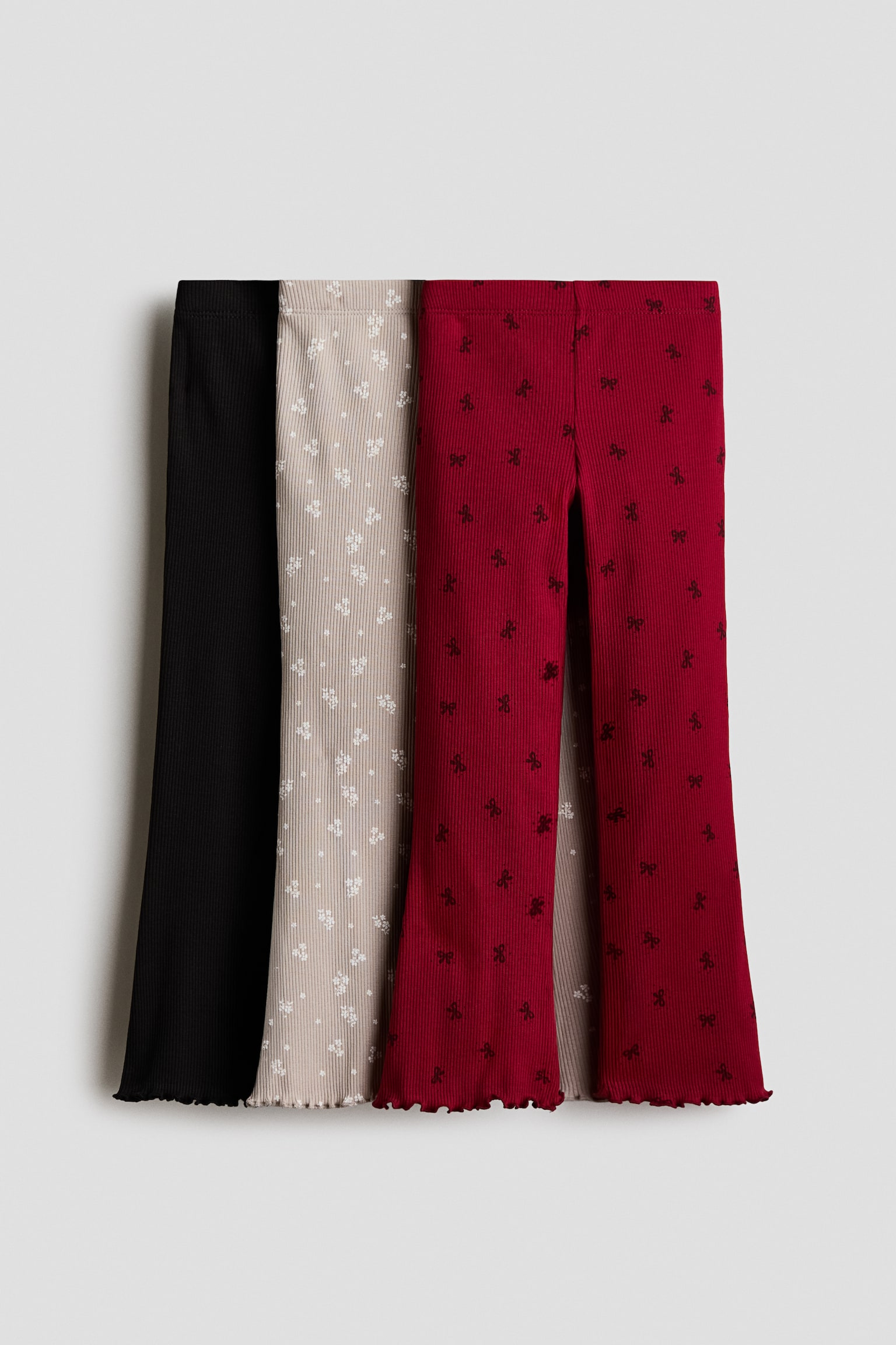 HÃ¡rom pÃ¡r bordÃ¡zott pamutjersey leggings lÃ¡thatÃ³ elÃ¶lnÃ©zetben, rugalmas derÃ©krÃ©sszel, bÅvÃ¼lÅ szÃ¡rakkal Ã©s hullÃ¡mos overlockolt szegÃ©llyel. A szett egy egyszÃ­nÅ± fekete pÃ¡rt, egy vilÃ¡gos bÃ©zs, aprÃ³ fehÃ©r virÃ¡gmintÃ¡s pÃ¡rt, valamint egy sÃ¶tÃ©tvÃ¶rÃ¶s, fekete masnismintÃ¡s pÃ¡rt tartalmaz.