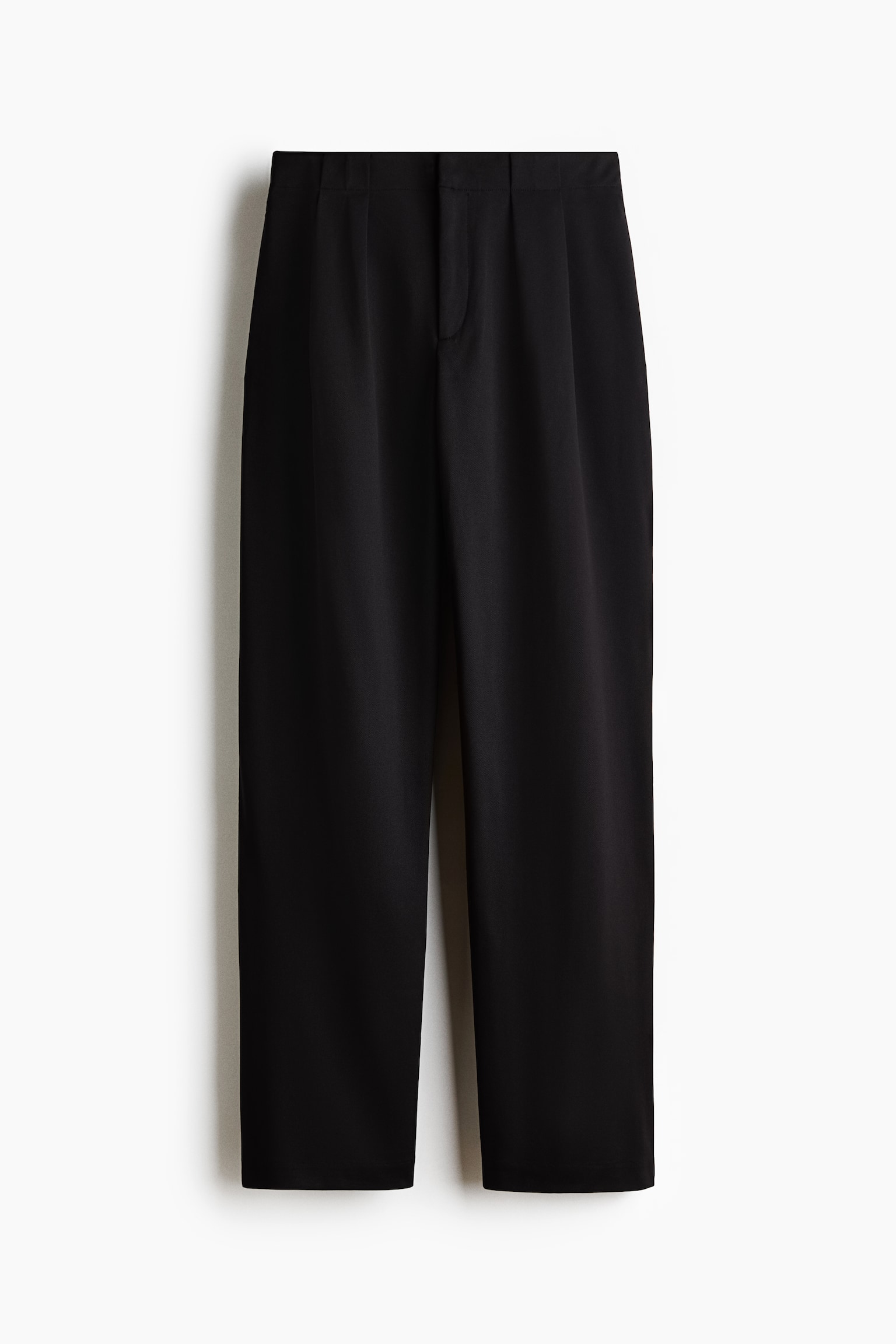 I pantaloni neri su misura sono mostrati frontalmente, con una vita pulita con pieghe frontali e una chiusura con patta nascosta. I pantaloni sono progettati con gambe leggermente affusolate, caratterizzate da una piega sottile che scende lungo il centro.
