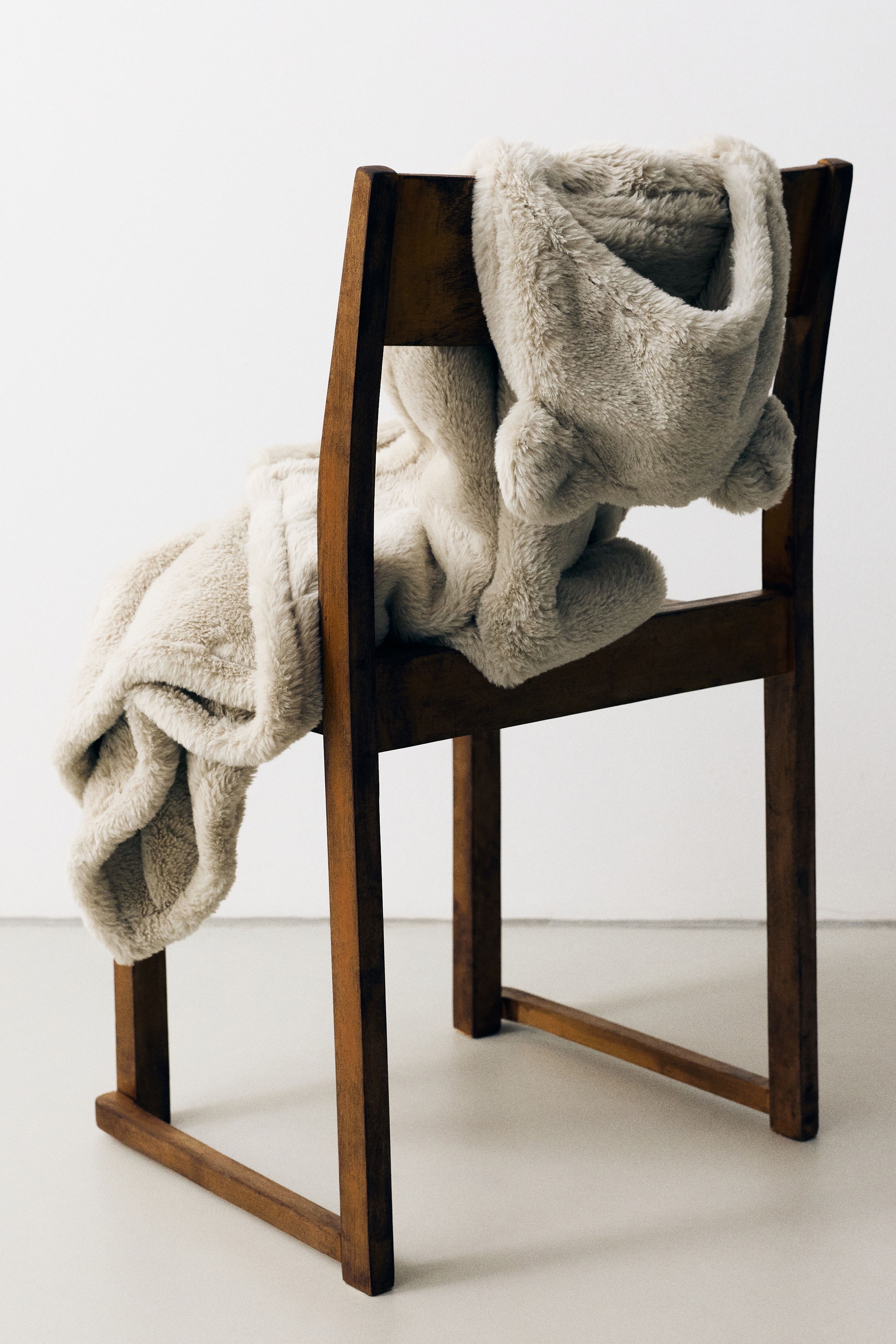 Eine hellbeige, kuschelige Fleece-Kapuzendecke hÃ¤ngt in einer Frontalansicht und verfÃ¼gt Ã¼ber eine Kapuze mit zwei kleinen, abgerundeten Tierohren oben. Die vorne offene Decke fÃ¤llt in weichen Falten nach unten und zeigt auf der Innen- wie Aussenseite einen flauschigen, strukturierten Stoff.