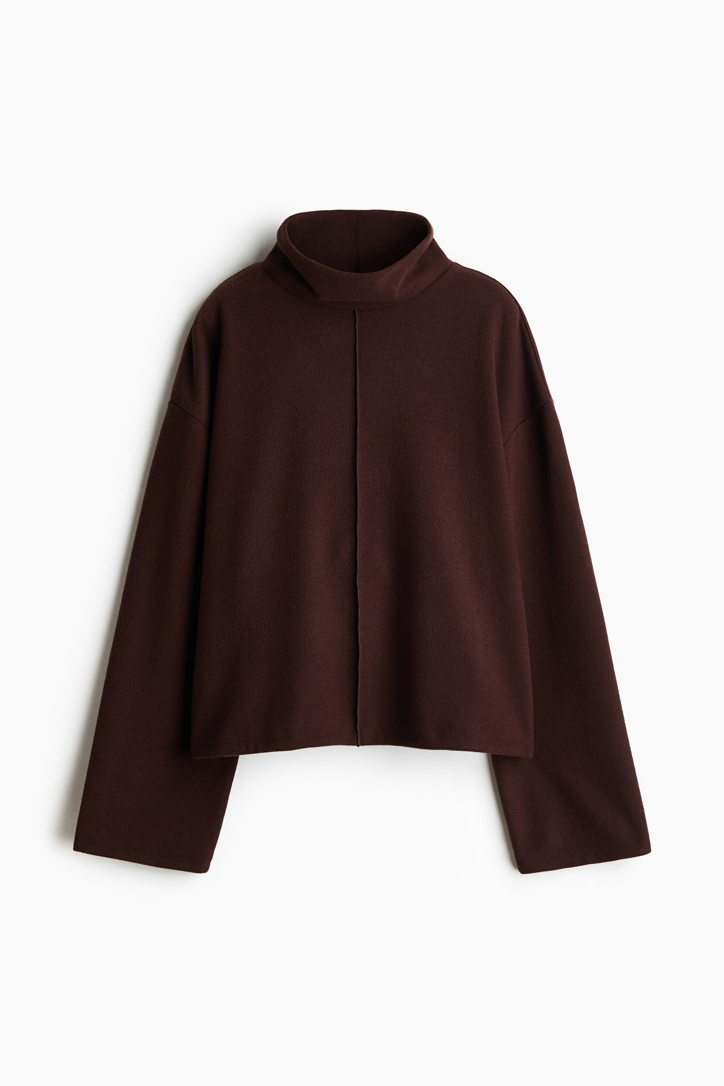 A dark brown, relaxed-fit knit sweater featuring a high neck, dropped shoulders, and a prominent centre-front seam is worn by the model. The sweater is styled with matching knit bottoms as the model poses with one hand raised near her hair.