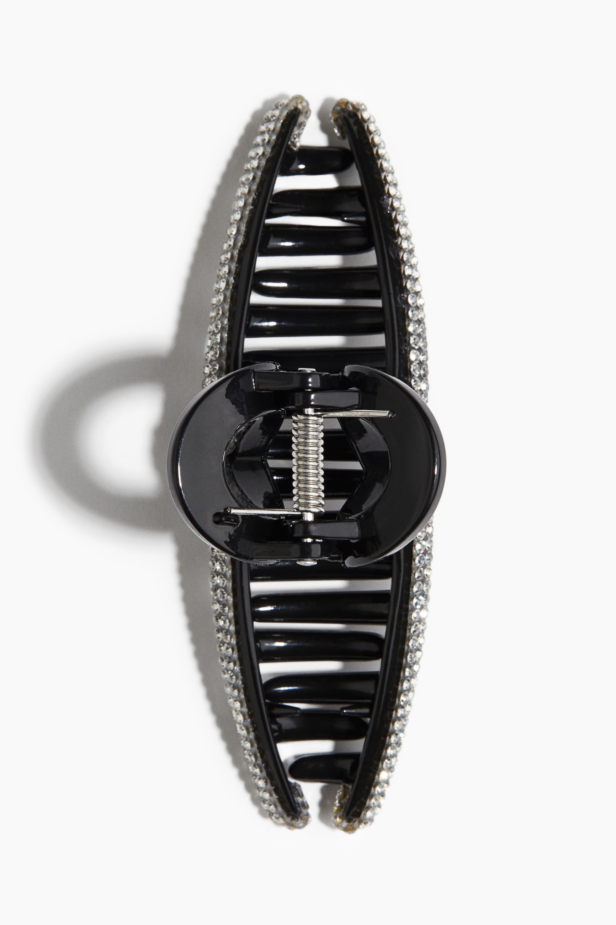 View larger image: A black claw hair clip is displaying clear rhinestones along its outer edges, and is featuring multiple inner teeth and a visible silver spring mechanism.