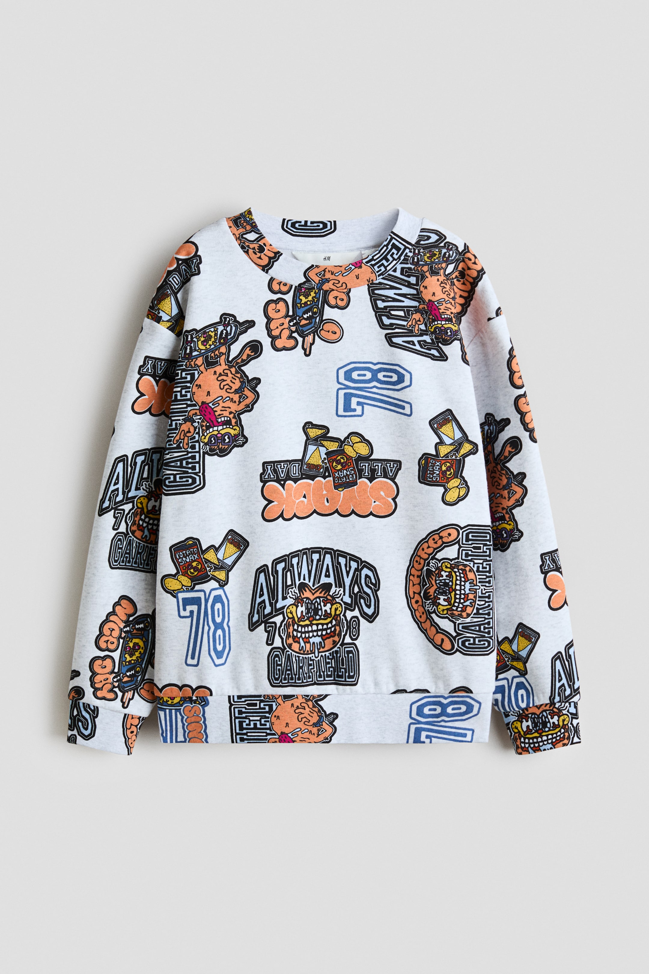 View larger image: A relaxed fit sweatshirt features an all-over print of stylised Garfield characters with snacks and text reading 'ALWAYS GARFIELD' and '78' in orange, black, blue and yellow on a light grey base. The front view shows a round, rib-trimmed neckline, dropped shoulders, long sleeves and ribbing finishing the cuffs and hem.