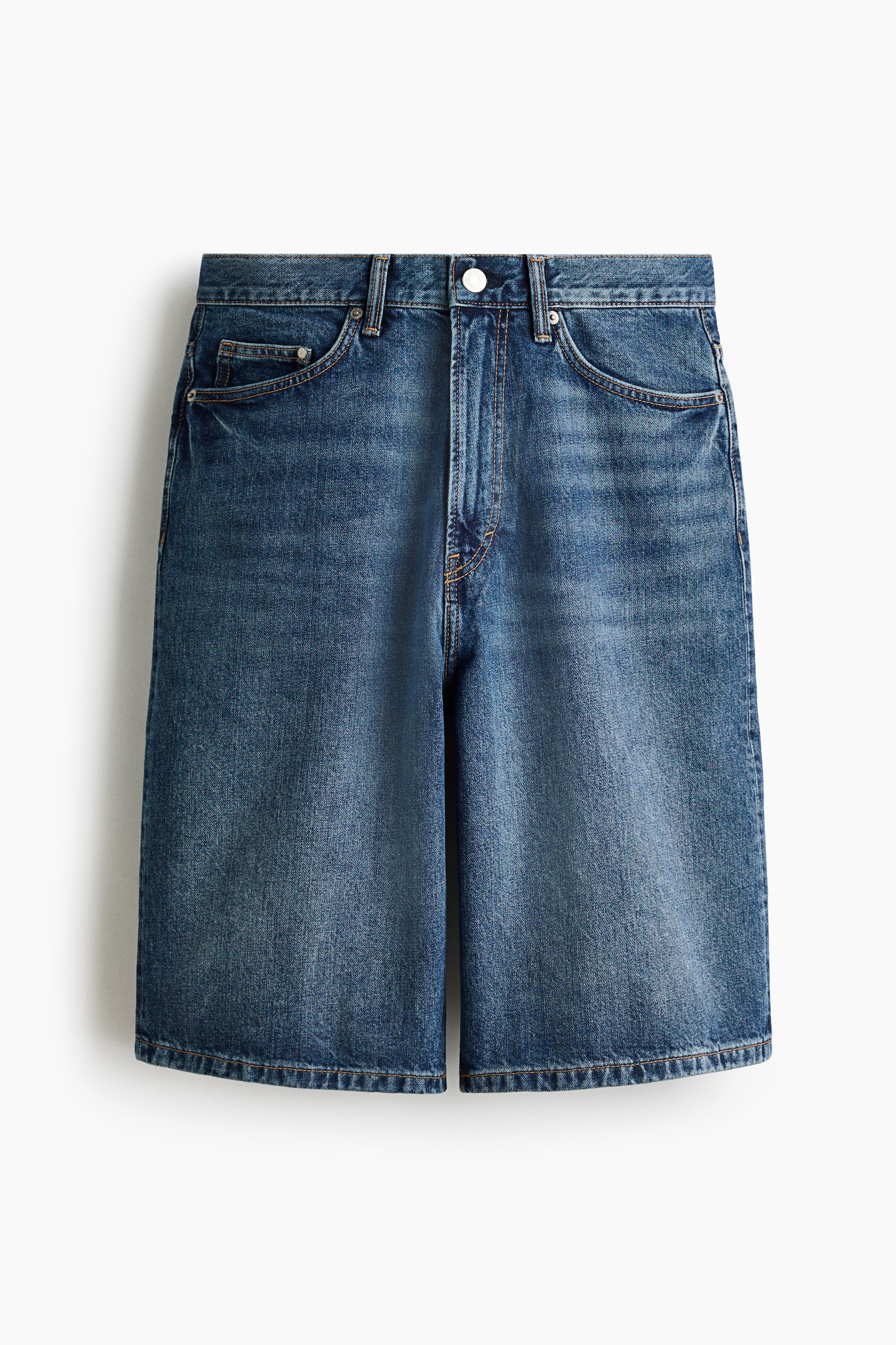 View larger image: Front view of 5-pocket rigid cotton denim shorts featuring a regular waist, a zip fly, and a dropped crotch. The shorts are cut with a rounded leg and a baggy fit that offers ample room throughout the leg.