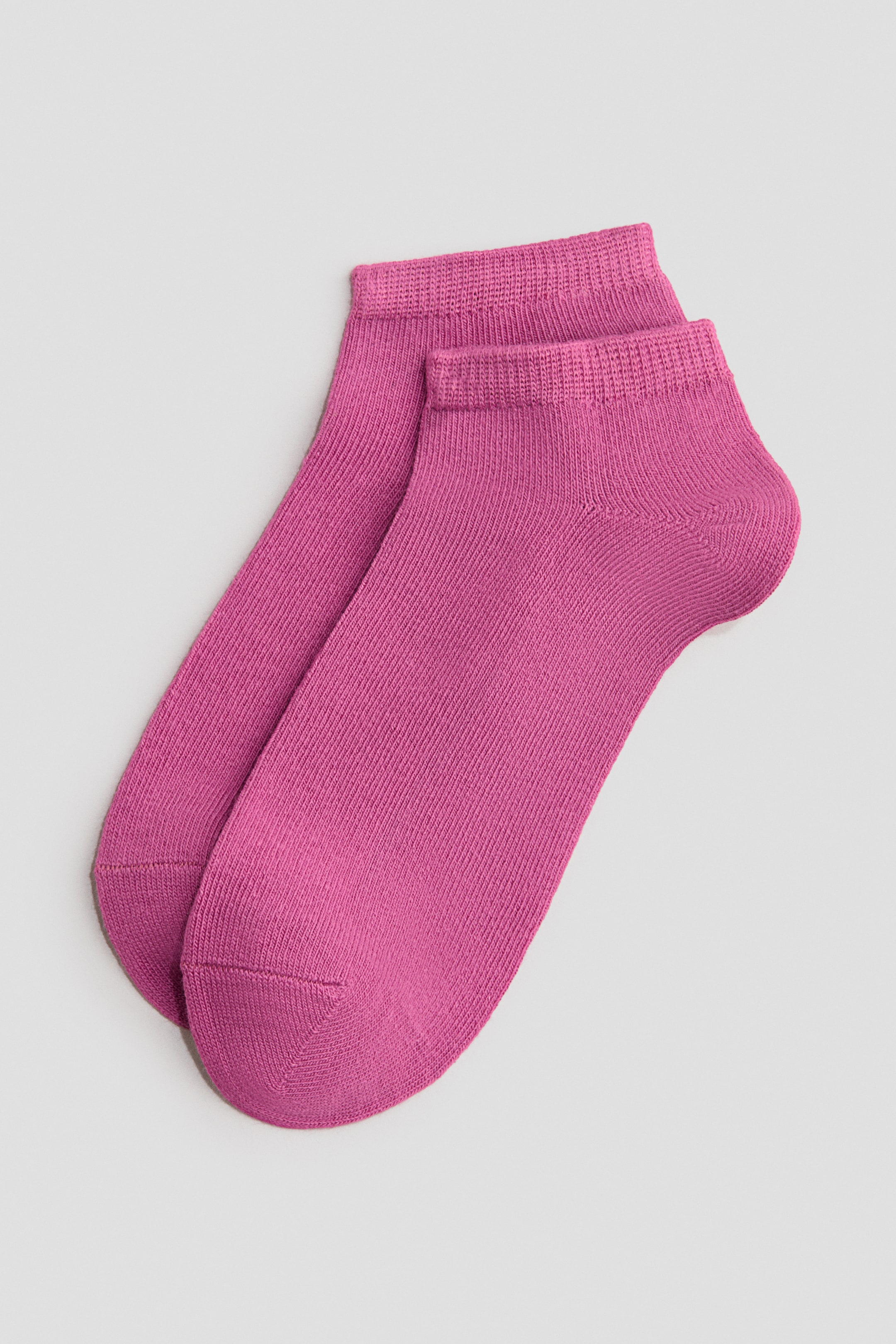 Voir une image plus grande: Une paire de chaussettes de sport roses est posée à plat, légèrement superposée. Les chaussettes en maille fine présentent une texture côtelée, des bords-côtes élastiques et des pointes et talons renforcés et lisses.