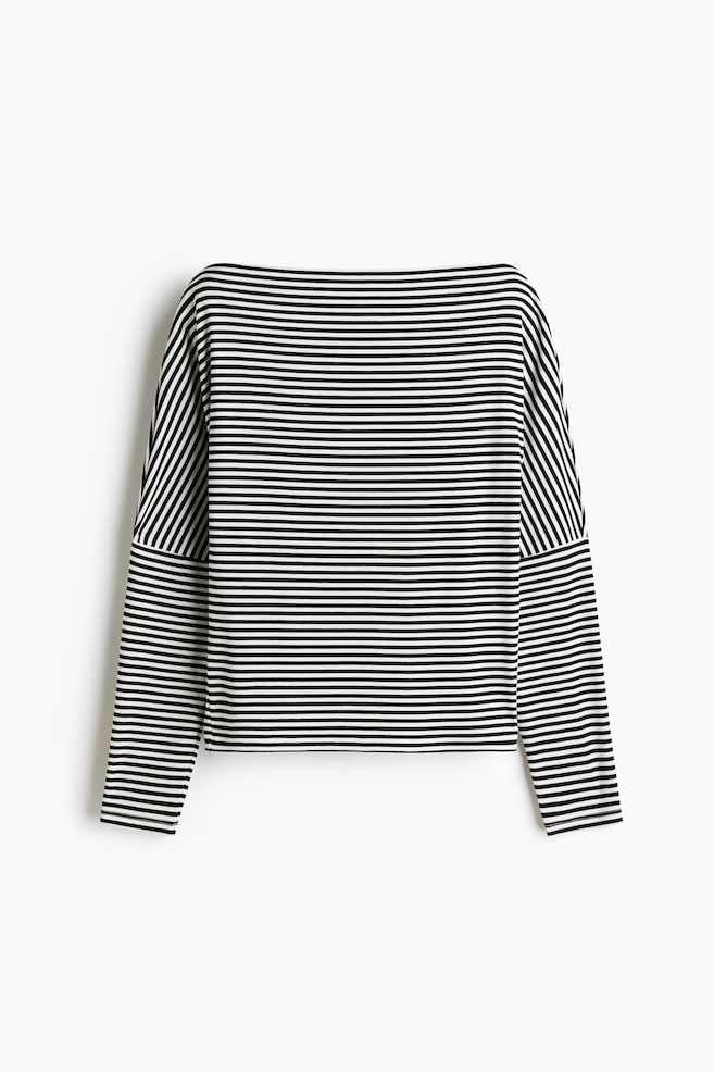 A long-sleeved top is laid flat, showcasing a pattern of thin black and white horizontal stripes. It features a boat neck and dropped shoulders. - 1