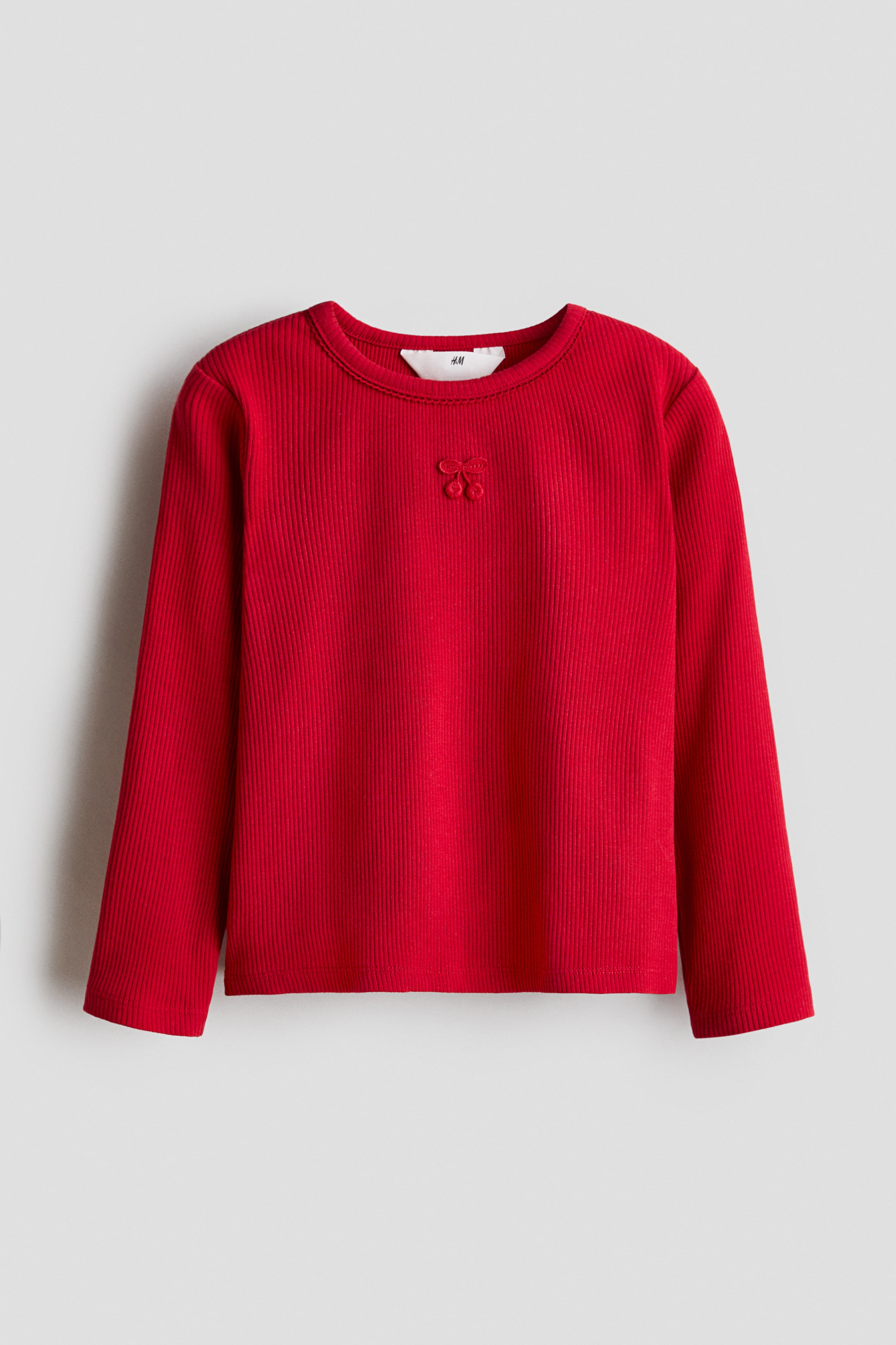 View larger image: A red, ribbed cotton-jersey top is shown from the front, featuring a round, picot-trimmed neckline, long sleeves, and a straight-cut hem, with a small embroidered cherry motif visible just below the neckline.