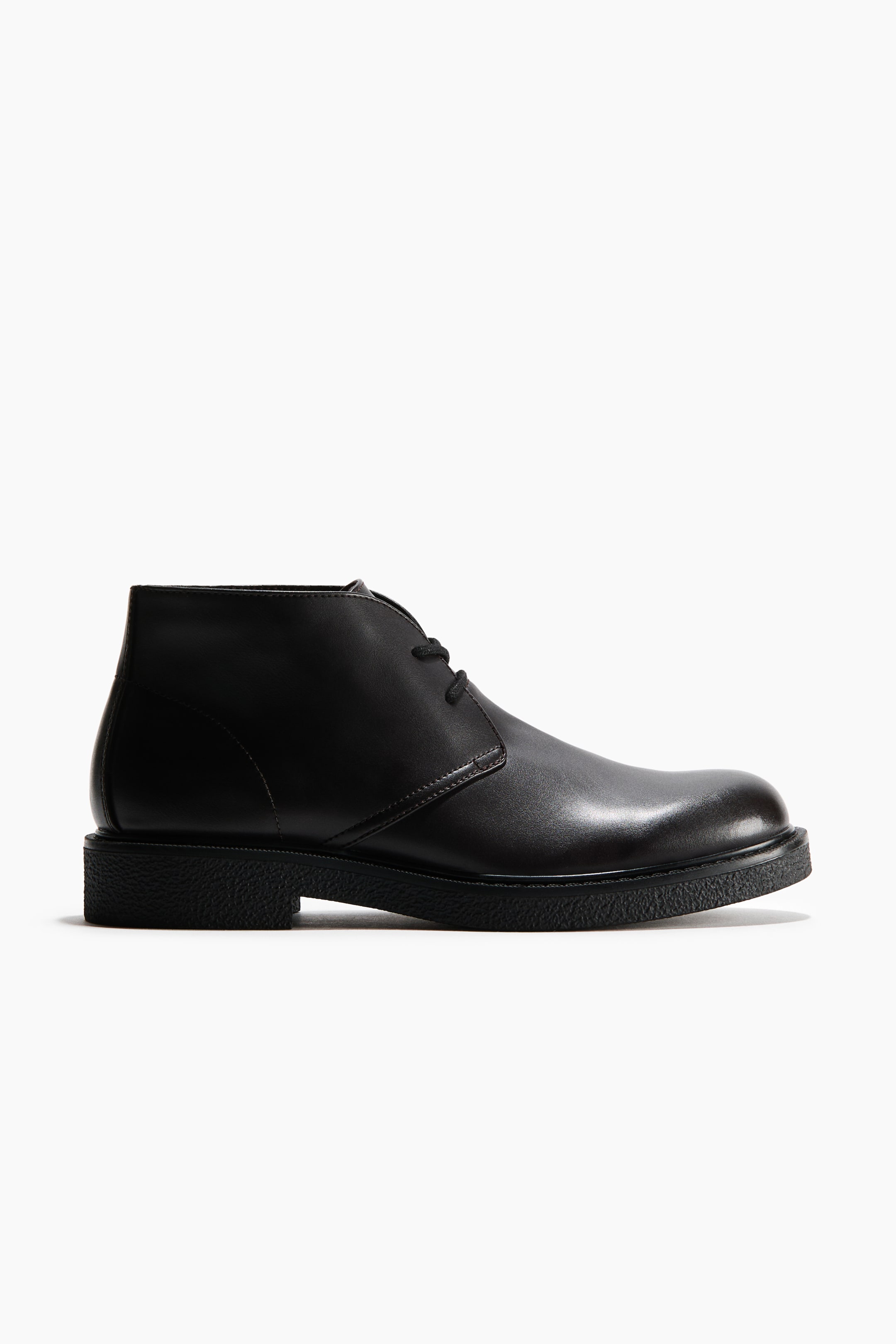 View larger image: A black leather chukka boot featuring a two-eyelet lace-up closure, a rounded toe, and a thick, textured black sole with a low block heel.