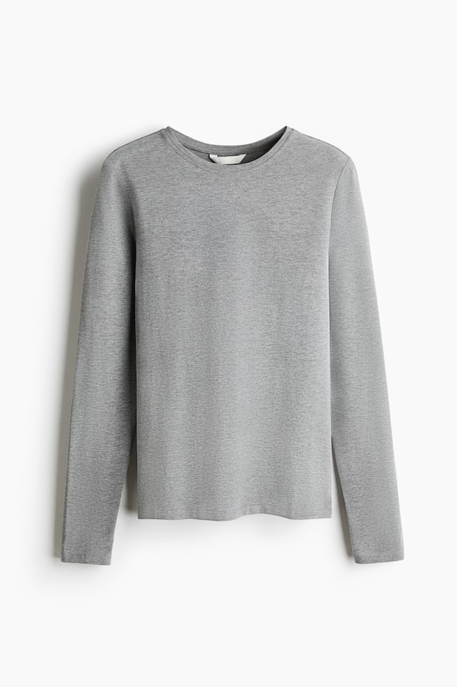 En grÃ¥, lÃ¥ngÃ¤rmad topp hÃ¤nger vÃ¤nd framÃ¥t och visar en rund halsringning, en figurnÃ¤ra siluett och en rak fÃ¥ll. Det mjuka bomullsjerseytyget har ett ljusgrÃ¥tt melerat mÃ¶nster med enkla sydda avslutningar. - 1