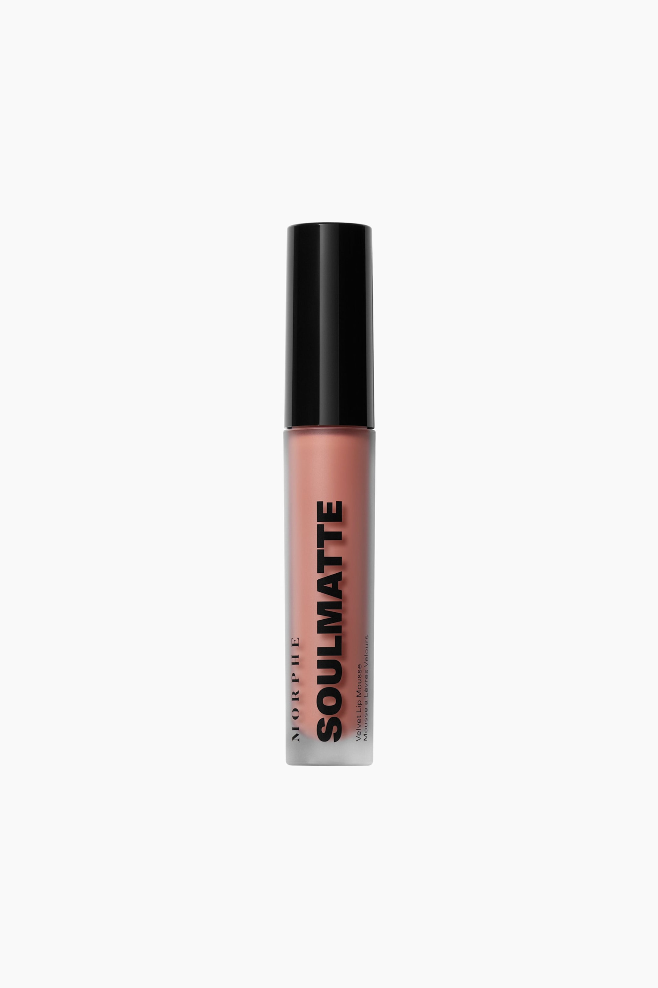 Se større billede: En Morphe Soulmatte Velvet Lip Mousse står oprejst og præsenterer et gennemskinneligt cylindrisk rør fyldt med et fersken-nude farvet produkt. Røret har en solid sort cylindrisk hætte og mærketeksten "Morphe" og "Soulmatte Velvet Lip Mousse" trykt vertikalt.