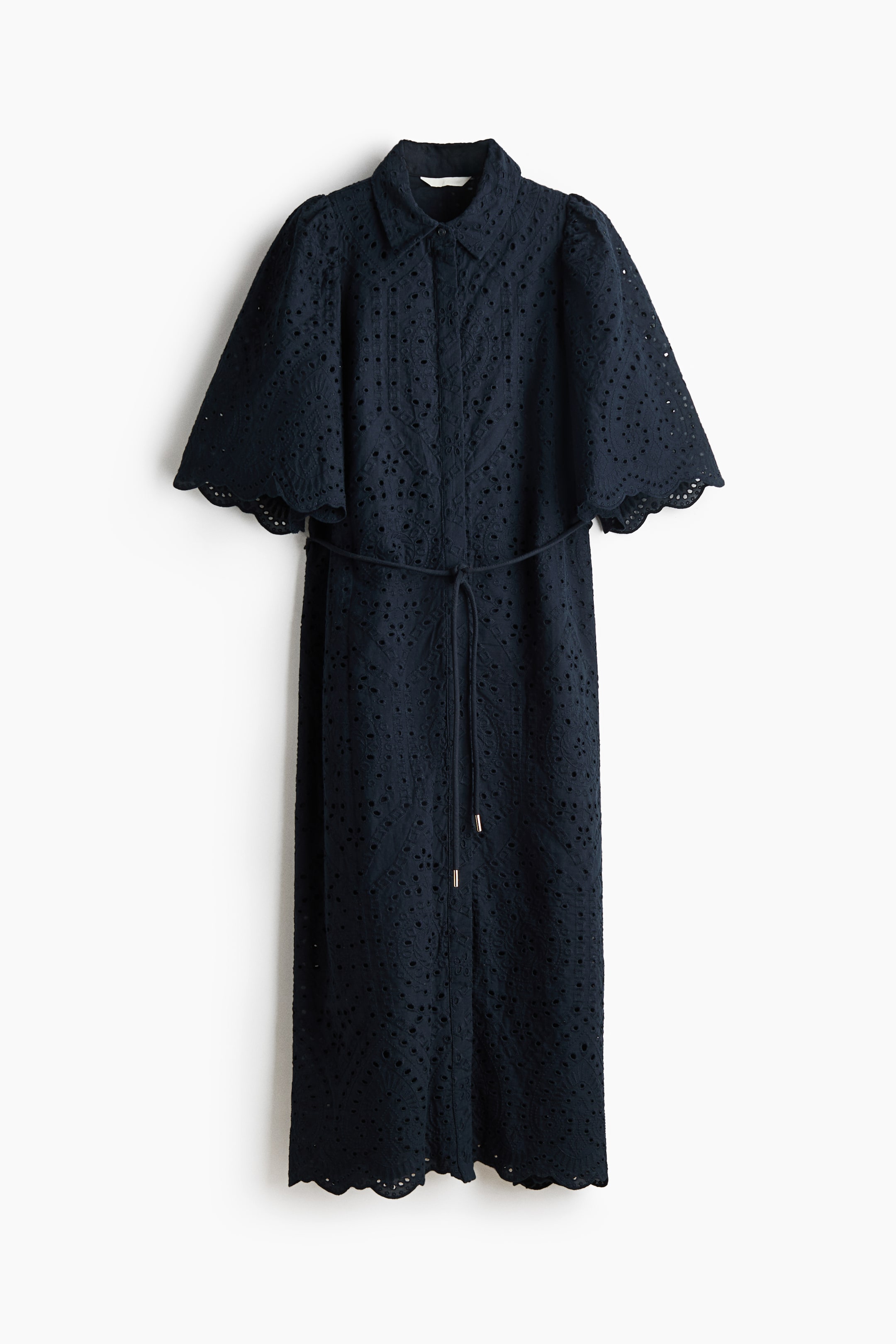 View larger image: A dark blue broderie anglaise shirt dress features a collar, a button-front placket, and short puffed sleeves with scalloped edges. A matching tie belt with metallic tips cinches the waist, and the dress ends in a scalloped hem.
