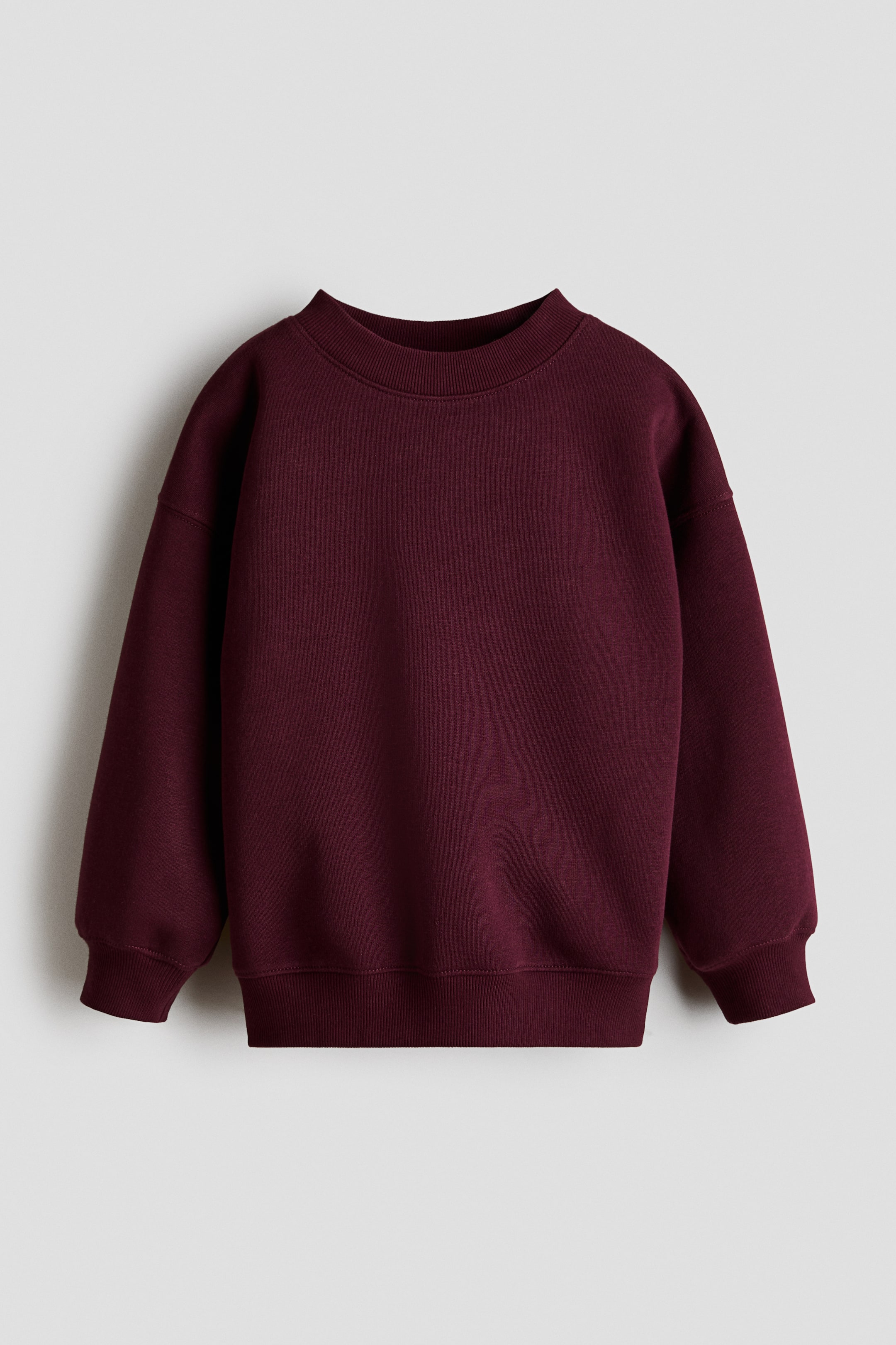 View larger image: The maroon sweatshirt is displayed from the front, showcasing a ribbed crew neck, long sleeves with ribbed cuffs, and a ribbed hem.