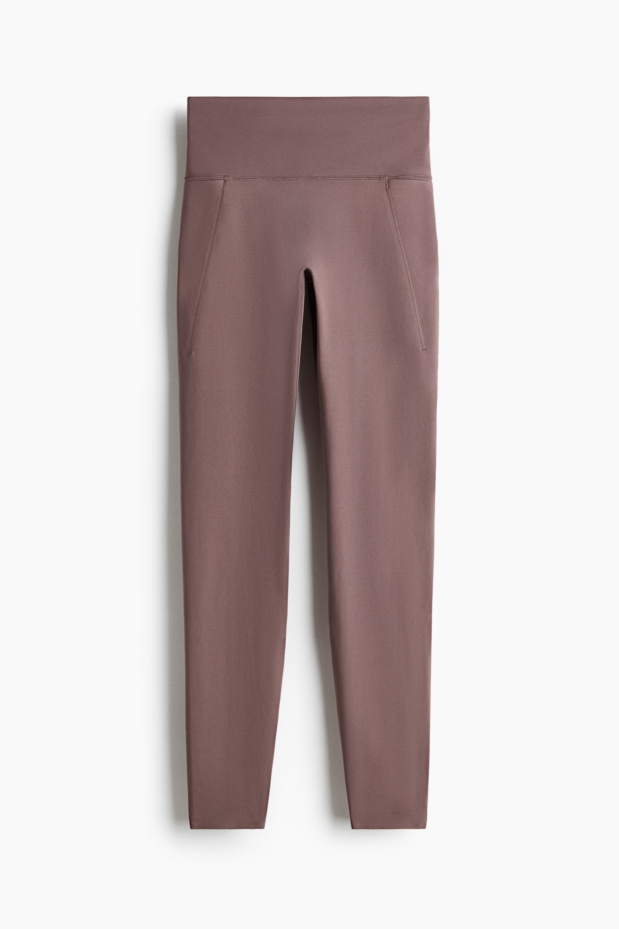 View larger image: Front-facing sports leggings in a muted mauve hue are being presented. They are featuring a wide, high-rise waistband and are incorporating slanted, inset pockets on both sides of the hips.