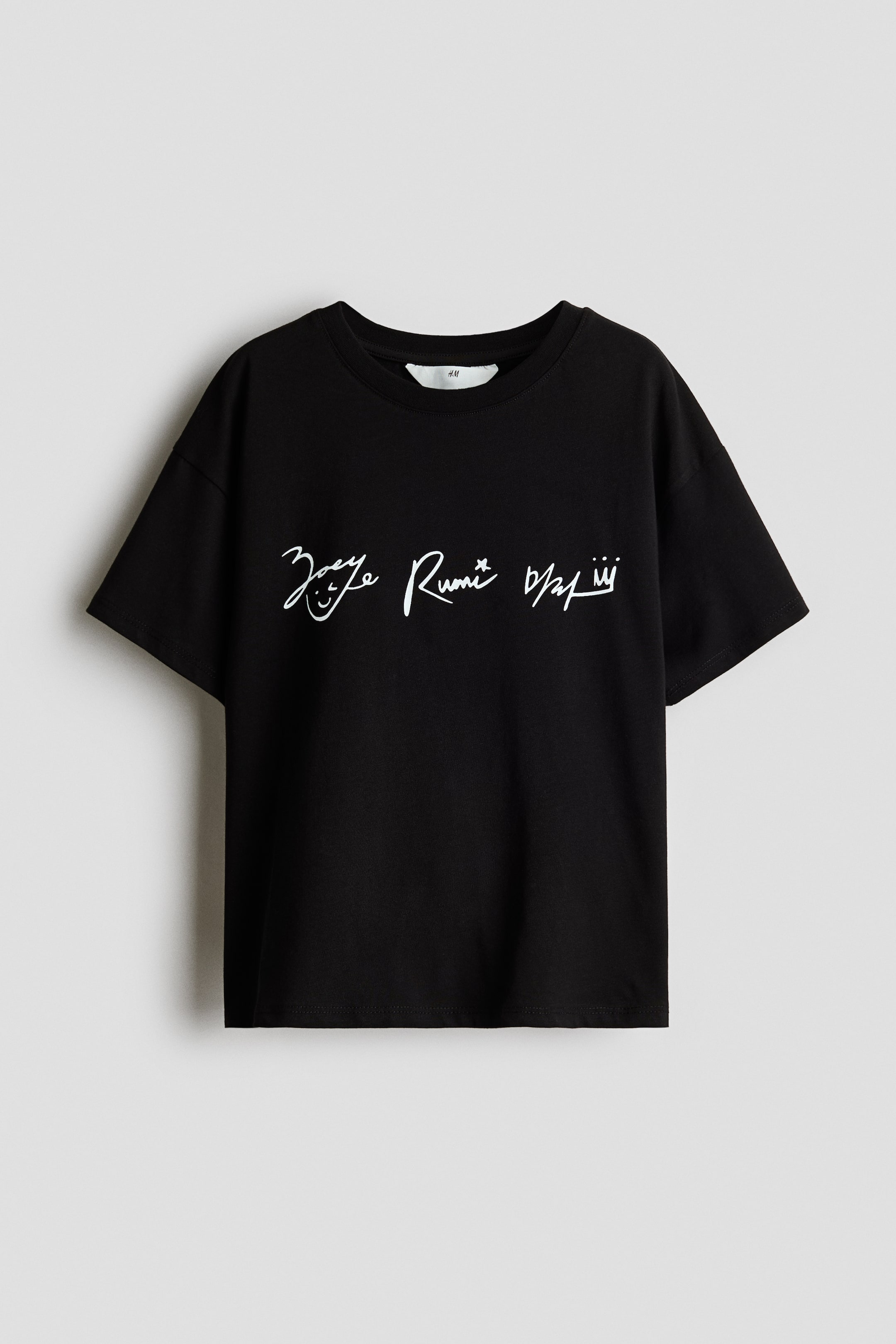 Grösseres Bild ansehen: Ein schwarzes T-Shirt wird von vorne präsentiert, mit einem weißen, handgeschriebenen Druck, der ein Smiley-Gesicht und eine Krone auf der Brust zeigt. Es ist mit einem runden, gerippten Ausschnitt und sanft fallenden Schultern gestaltet.
