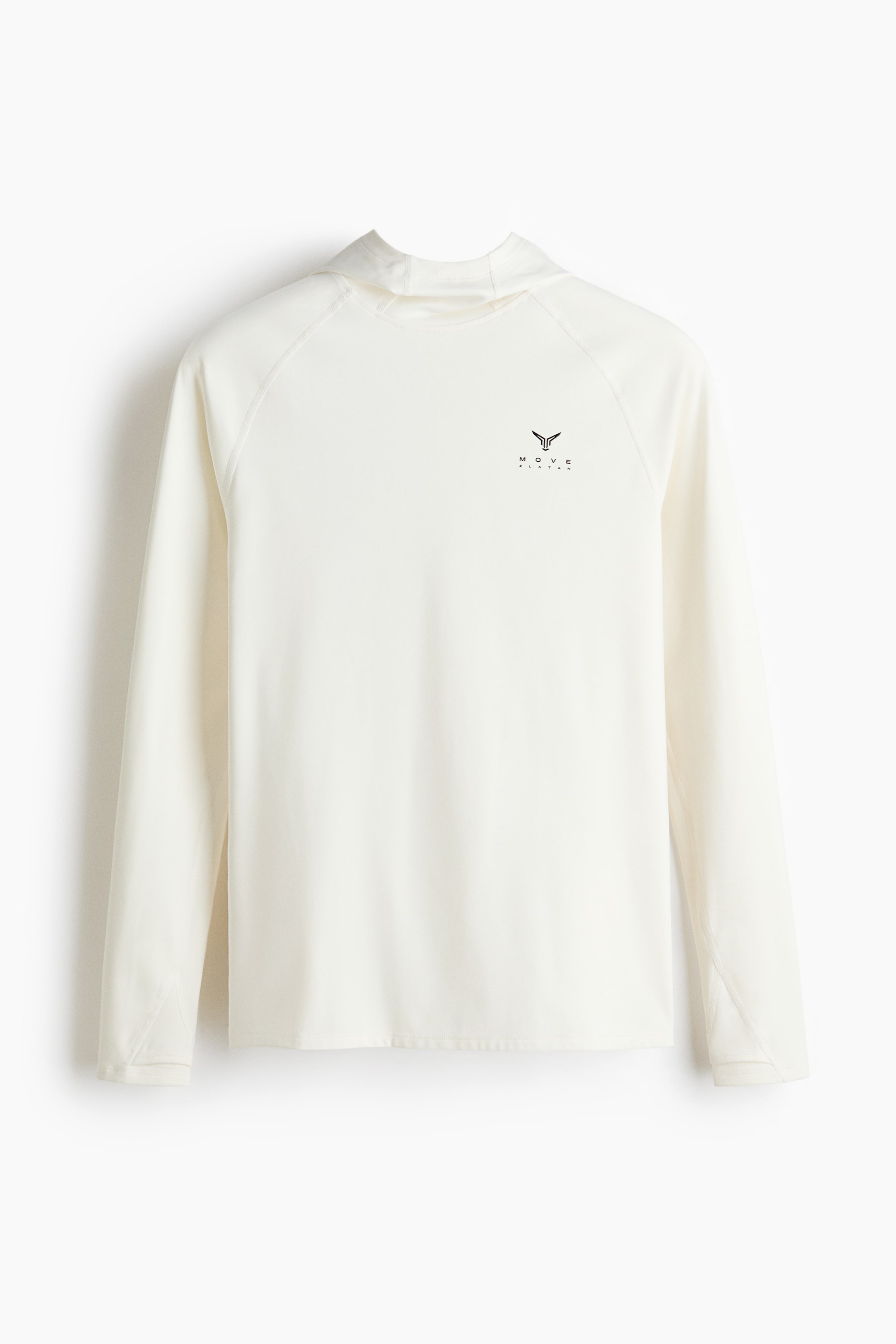 Ampliar la imagen: Una camiseta de manga larga con capucha de color crema está mostrando su frente. Presenta mangas raglán, un escote alto formado por una capucha doblada hacia atrás y un logotipo estilizado negro en el pecho izquierdo.