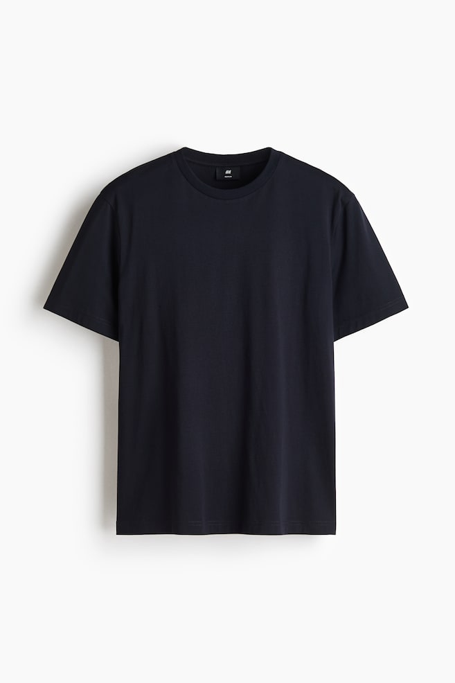 Una camiseta azul marino oscuro cuelga en plano y de frente, mostrando un cuello redondo acanalado, mangas cortas y un bajo recto. La prenda de color liso presenta un ajuste regular con una textura limpia y suave. - 1