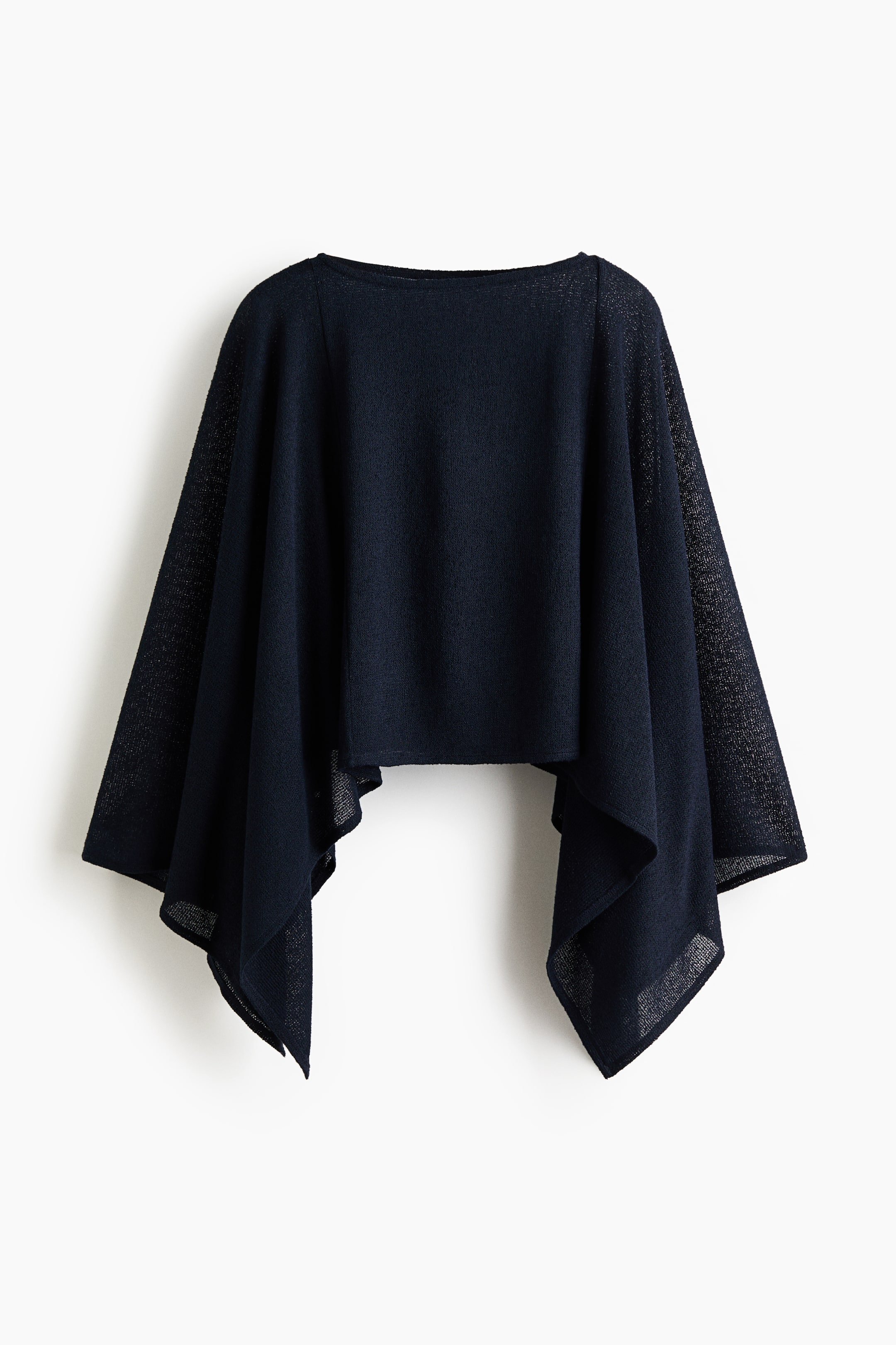 View larger image: This dark blue, short, loose-fit cape is shown from the front, highlighting a boat neckline, a handkerchief hem, and a fine knit texture with shimmering threads.