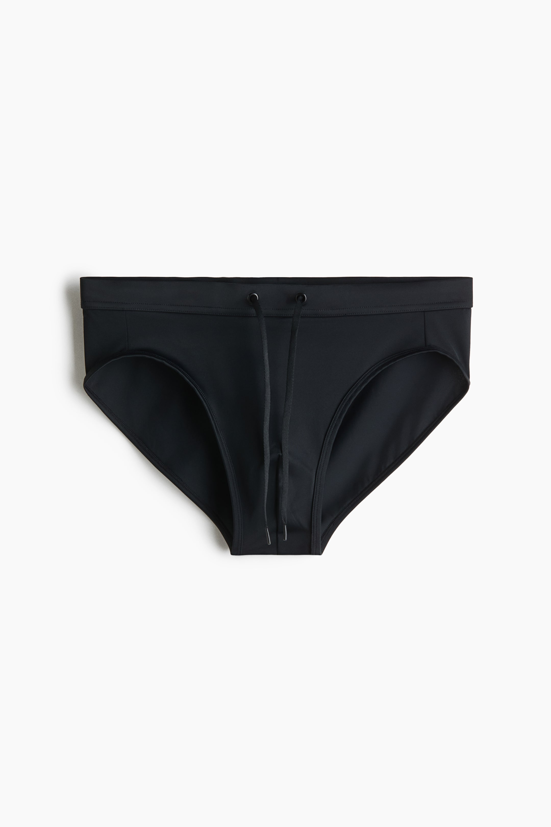 View larger image: A pair of solid black swim briefs is shown from the front, featuring an elasticized waistband with two metal eyelets and a black drawstring hanging down the front.