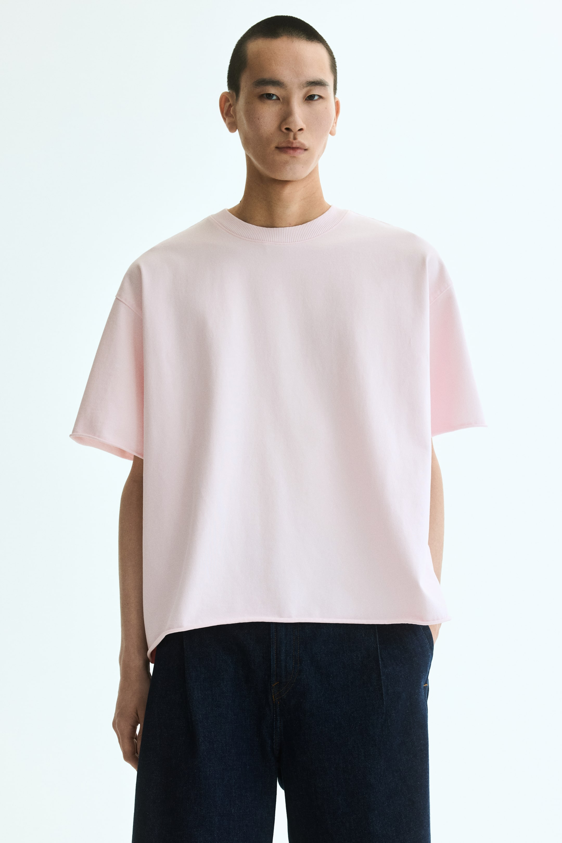 Voir une image plus grande: Un t-shirt rose de style ample en jersey de coton léger est présenté de face. Il est doté d'un col rond avec bordure côtelée, d'épaules tombantes et d'un ourlet droit, créant une silhouette surdimensionnée et très ample.