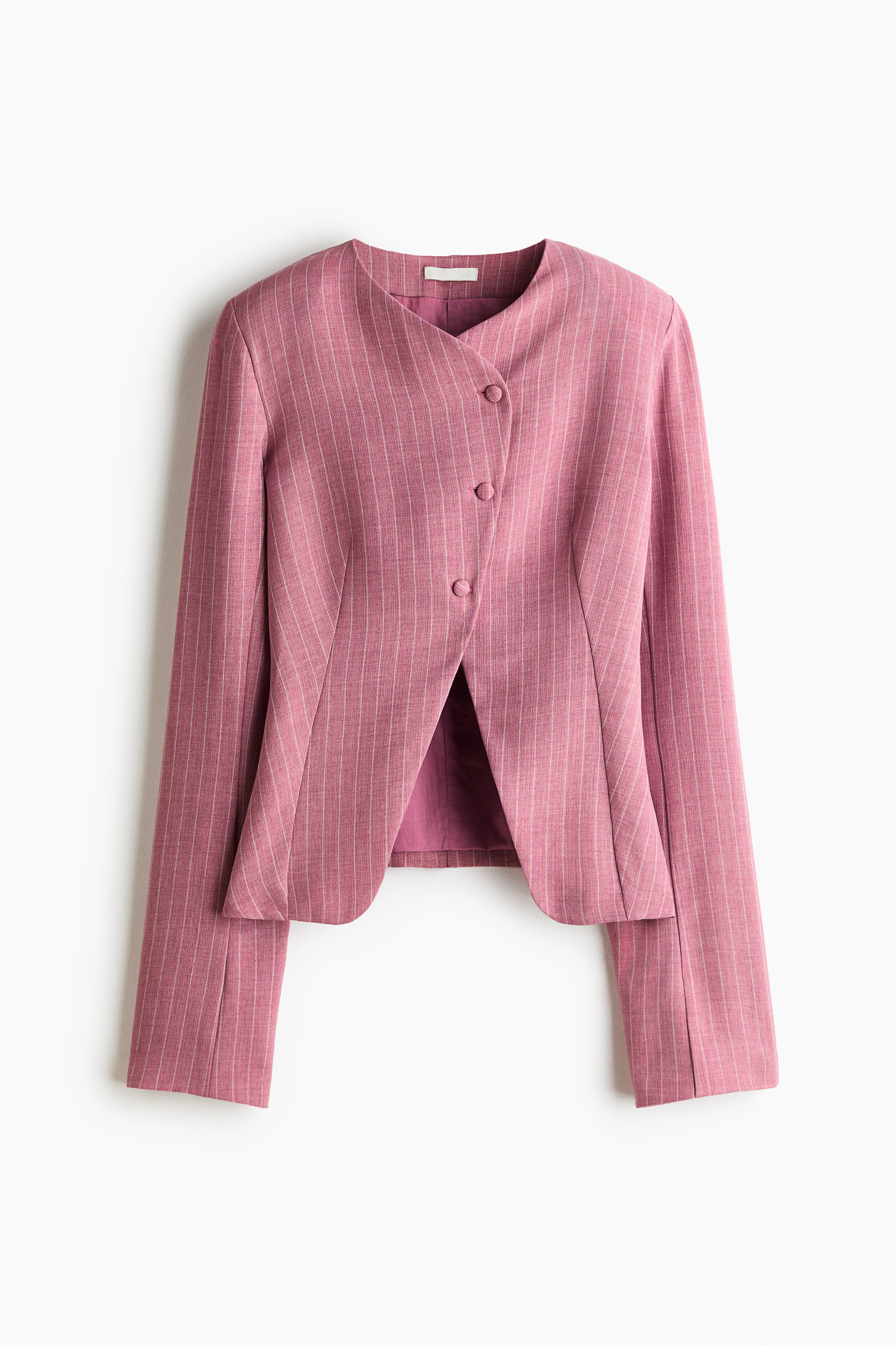 A pink pinstripe single-breasted blazer is shown from the front, featuring a lapelless neckline and a slightly offset, angled front opening with covered buttons at the top. The blazer showcases structured shoulder pads and waist darts, parting at the waist to reveal matching trousers.