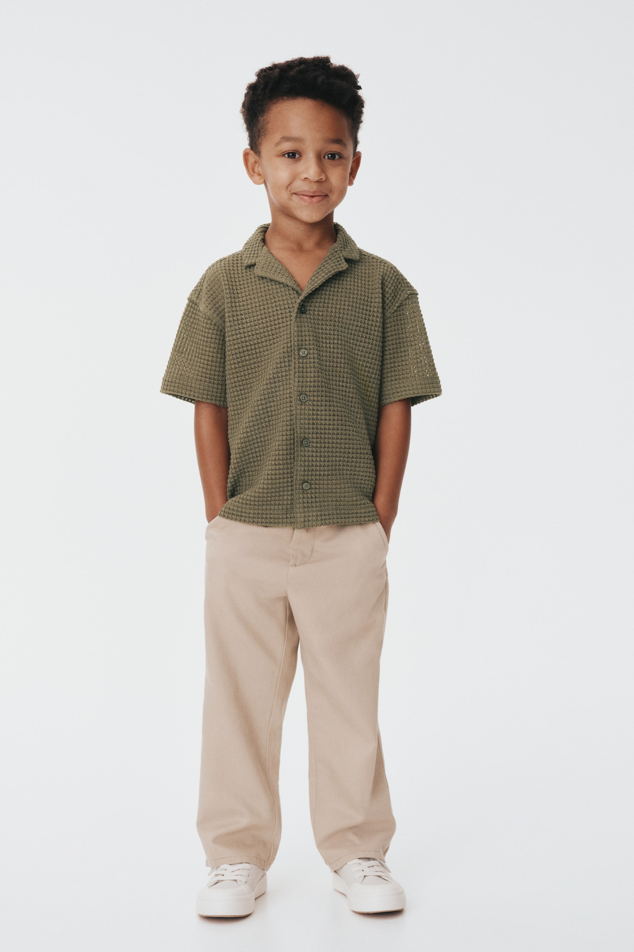Se større billede: Den oliven grønne vaffelstrikkede kortærmede skjorte præsenteres forfra og sidder løst. Den har en lejrbålkrave og en frontknapningsstolpe med mørke knapper.