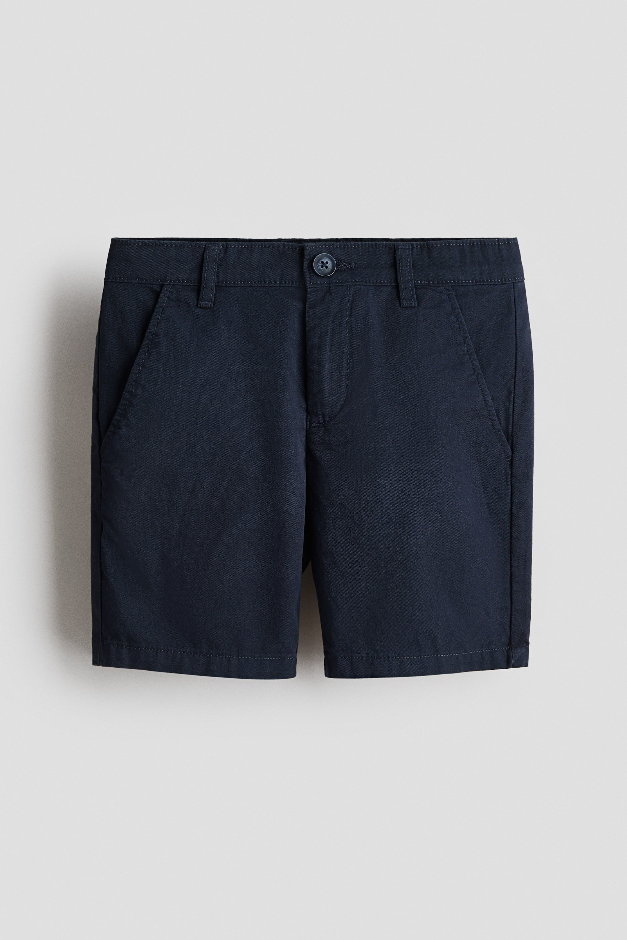 Grotere afbeelding bekijken: Donker marineblauwe shorts in zachte katoenen keperstof presenteren hun voorkant, met een knoopsluiting, ritssluiting en twee zijzakken met schuine opening.