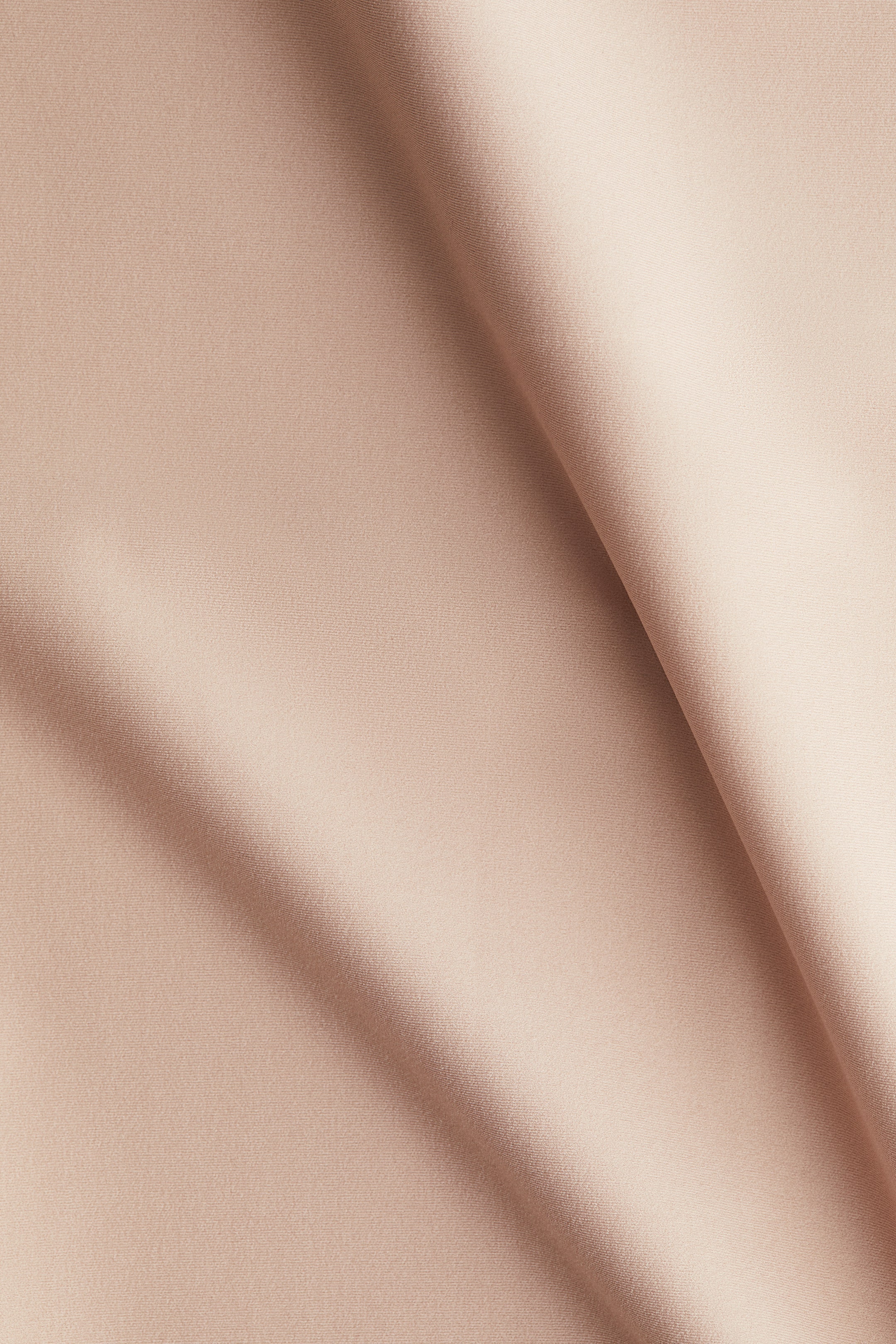 View larger image: A light peach-colored fabric with a subtle texture is draped, forming soft, flowing folds.