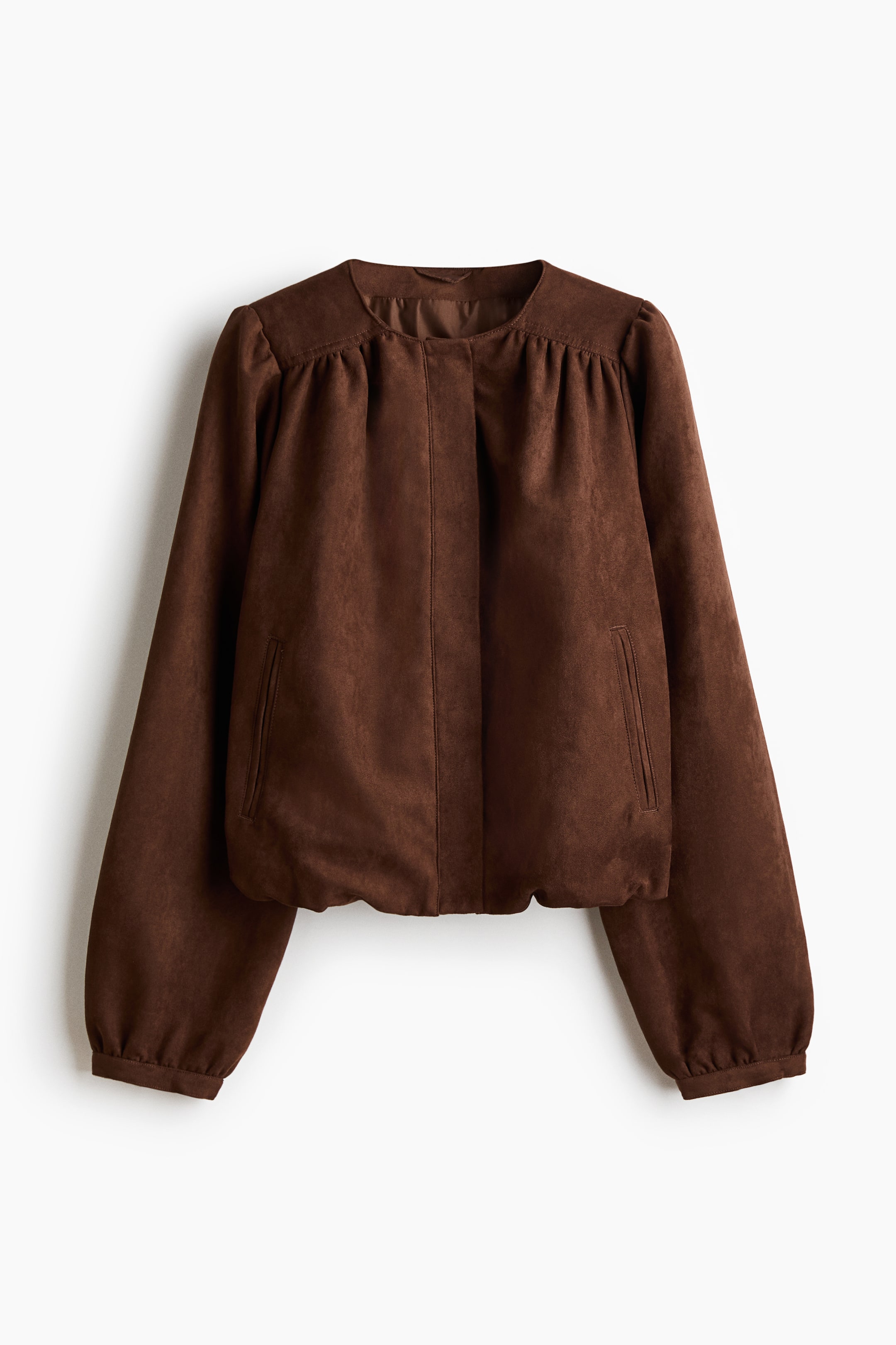 Ampliar la imagen: Una chaqueta marrón está presentando su FRENTE. Presenta una tela de tacto suave, un escote redondo sin cuello, un cierre frontal oculto y pliegues en la parte superior del pecho. Mangas voluminosas con puños recogidos y un dobladillo recogido completan el diseño, junto con dos bolsillos verticales en la parte frontal.