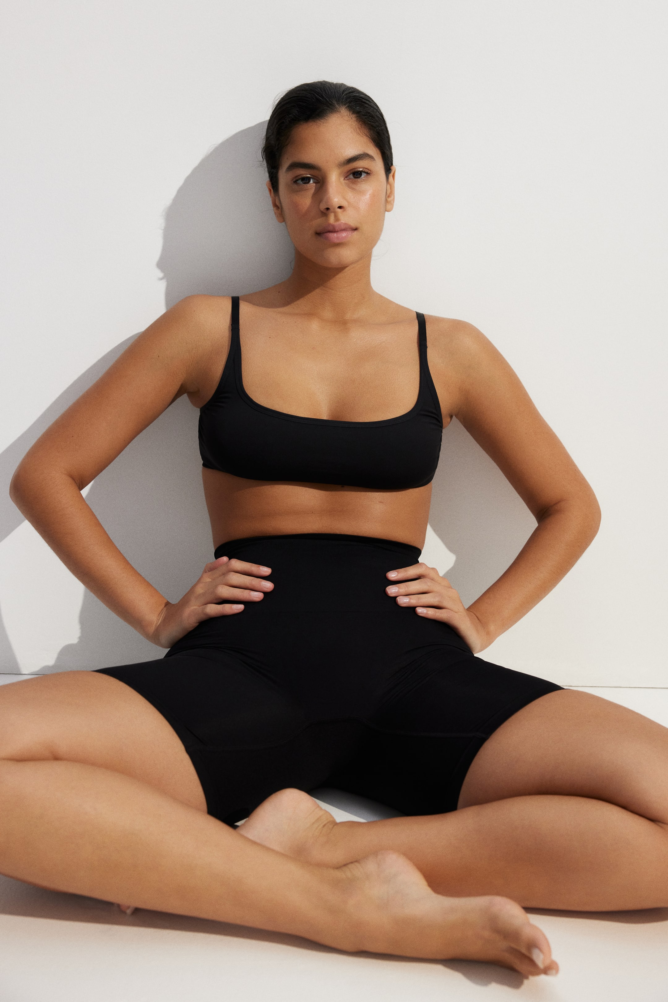 Ver imagen más grande: El conjunto negro de dos piezas consta de un sujetador con escote redondo hacia el frente y tirantes finos, acompañado de unos pantalones cortos de talle alto y ajuste ceñido a mitad del muslo.