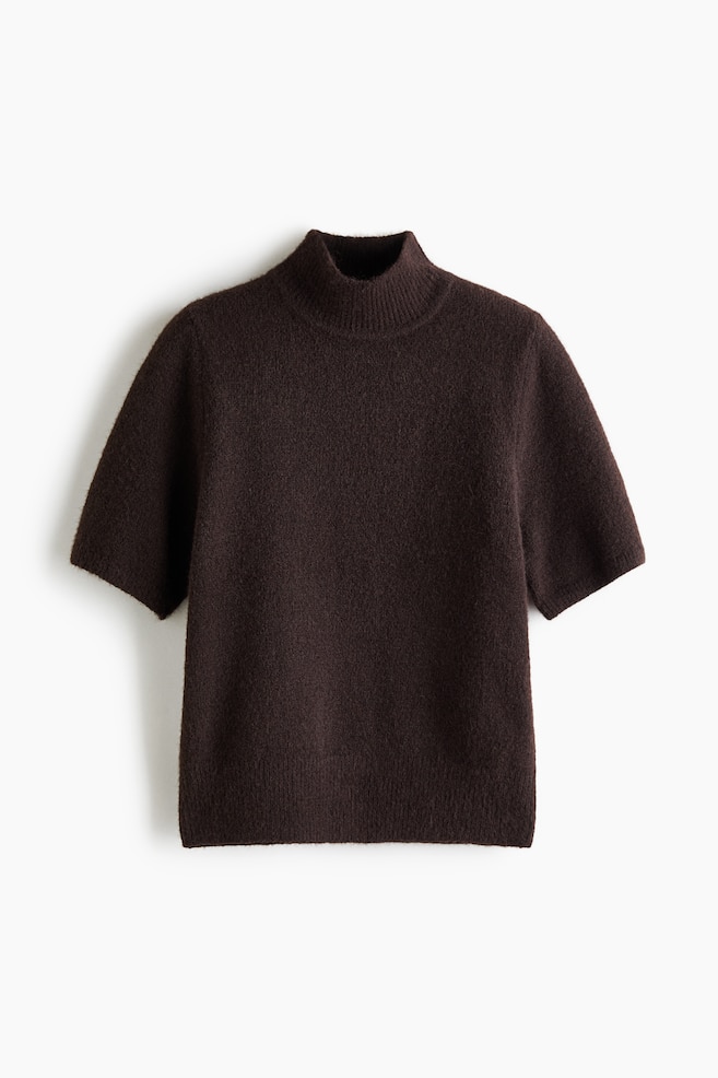 Un pull à manches courtes en maille duveteuse marron foncé est présenté de face, avec un col montant côtelé et un ourlet côtelé assorti. Le haut présente une finition douce et texturée, avec des manches amples arrivant au niveau des coudes. - 1