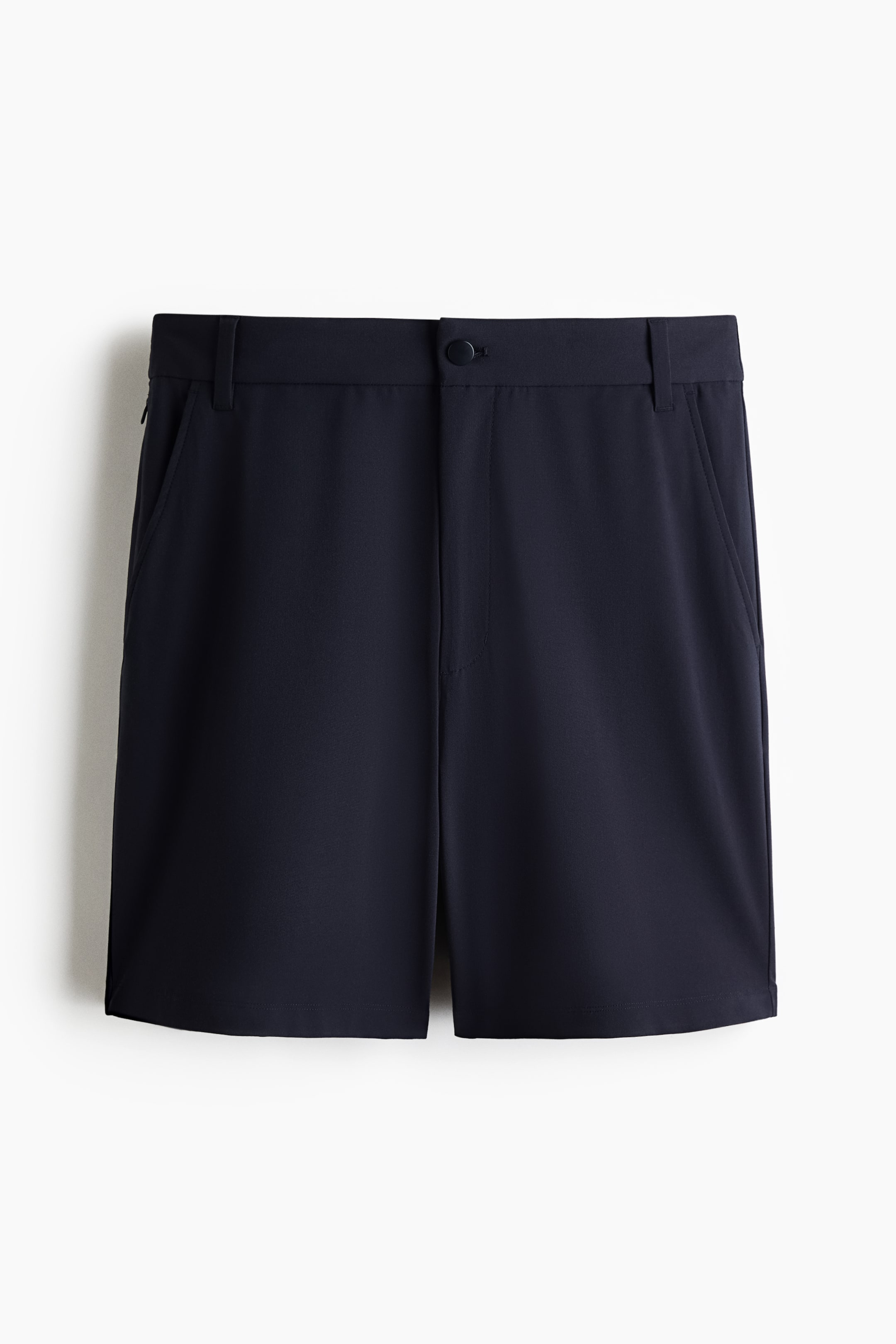 Ingrandisci l'immagine: I pantaloncini blu navy sono presentati in vista frontale, con una cintura piatta dotata di passanti per cintura e una chiusura a bottone singolo al centro davanti. Due tasche oblique a fessura appaiono sui lati anteriori, con una tasca aggiuntiva con cerniera visibile sulla cucitura laterale sinistra.