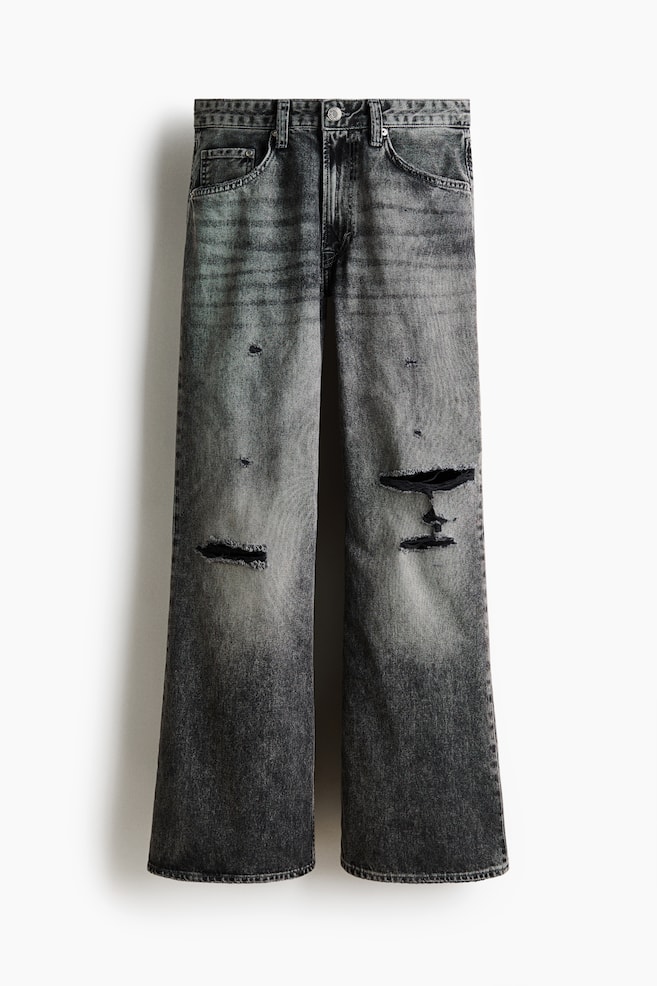 Jeans are presenting a dark gray, faded wash with prominent rips on both legs and other distressed details, shown from the front. They are designed with a regular waist, a button and zip fly closure, a 5-pocket style, and a loose fit with a gently flared leg. - 1