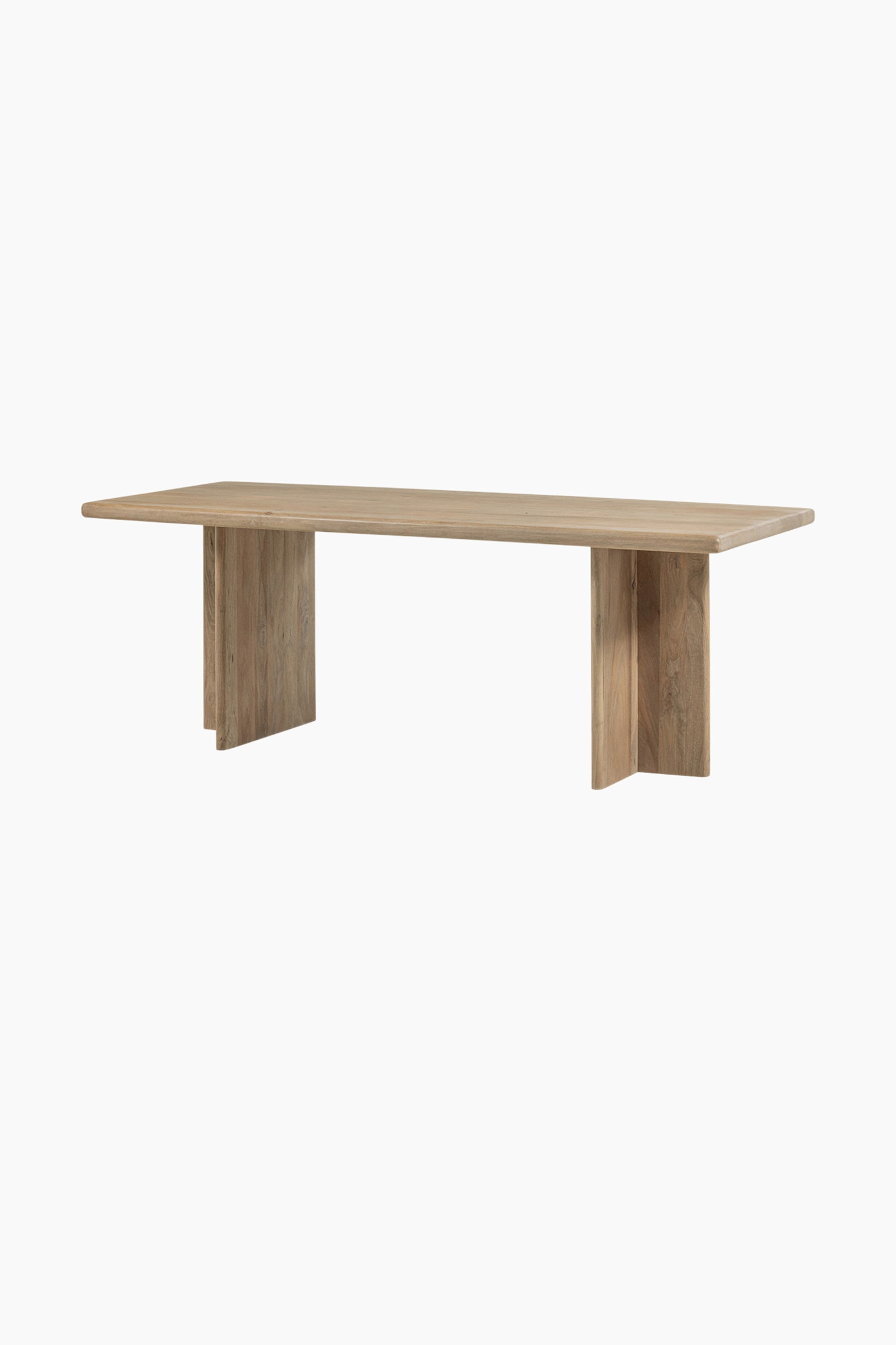 Agrandir l'image: Une table à manger rectangulaire en bois est présentée sous un léger angle, mettant en valeur sa finition brun clair et son grain de bois visible. Elle est dotée d'un plateau épais soutenu par deux pieds de piédestal substantiels et inclinés.