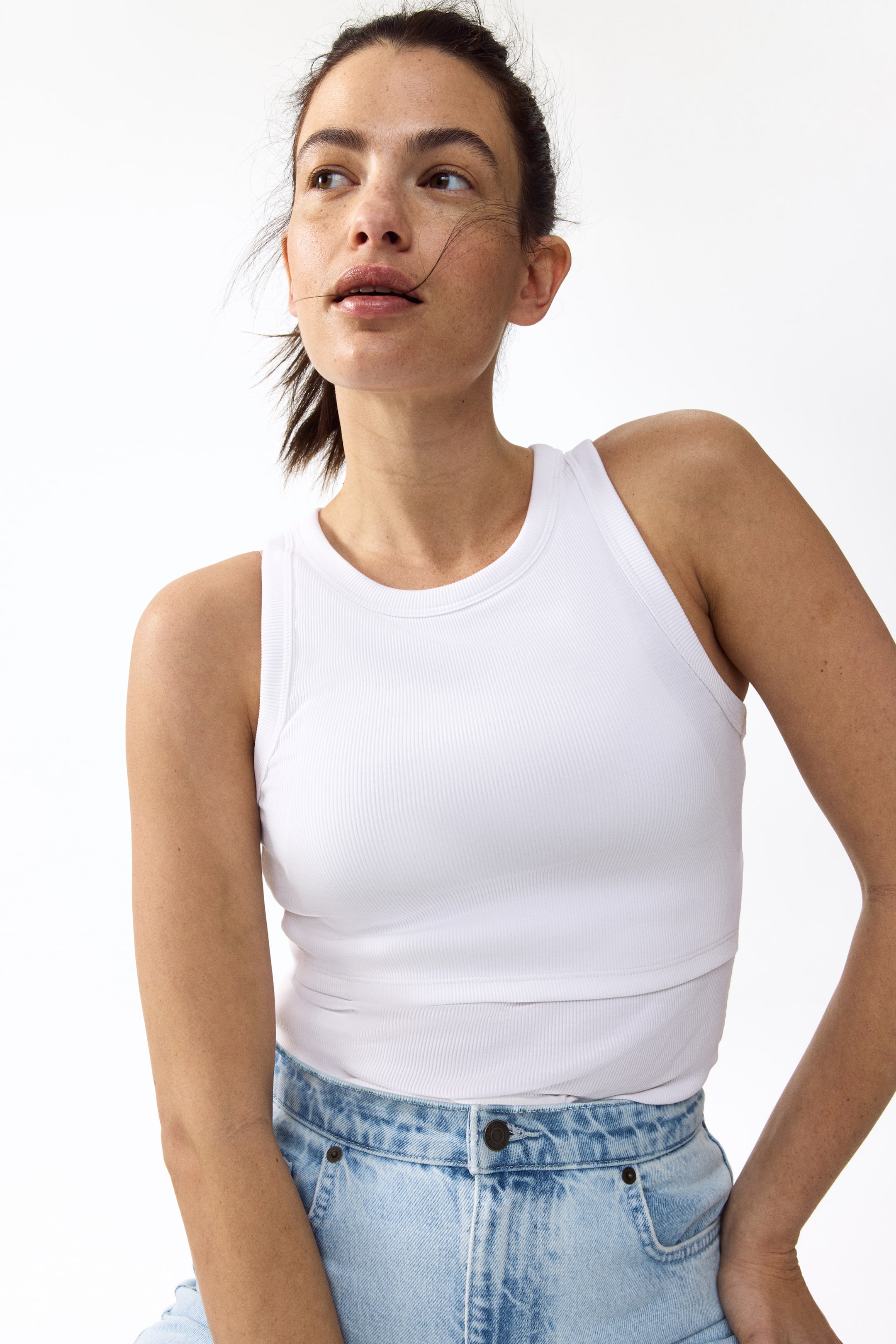 View larger image: The model is wearing a fitted vest top crafted from ribbed cotton jersey. It boasts a round neckline, narrow ribbed trim around the neckline and armholes, and a visible double layer at the top.