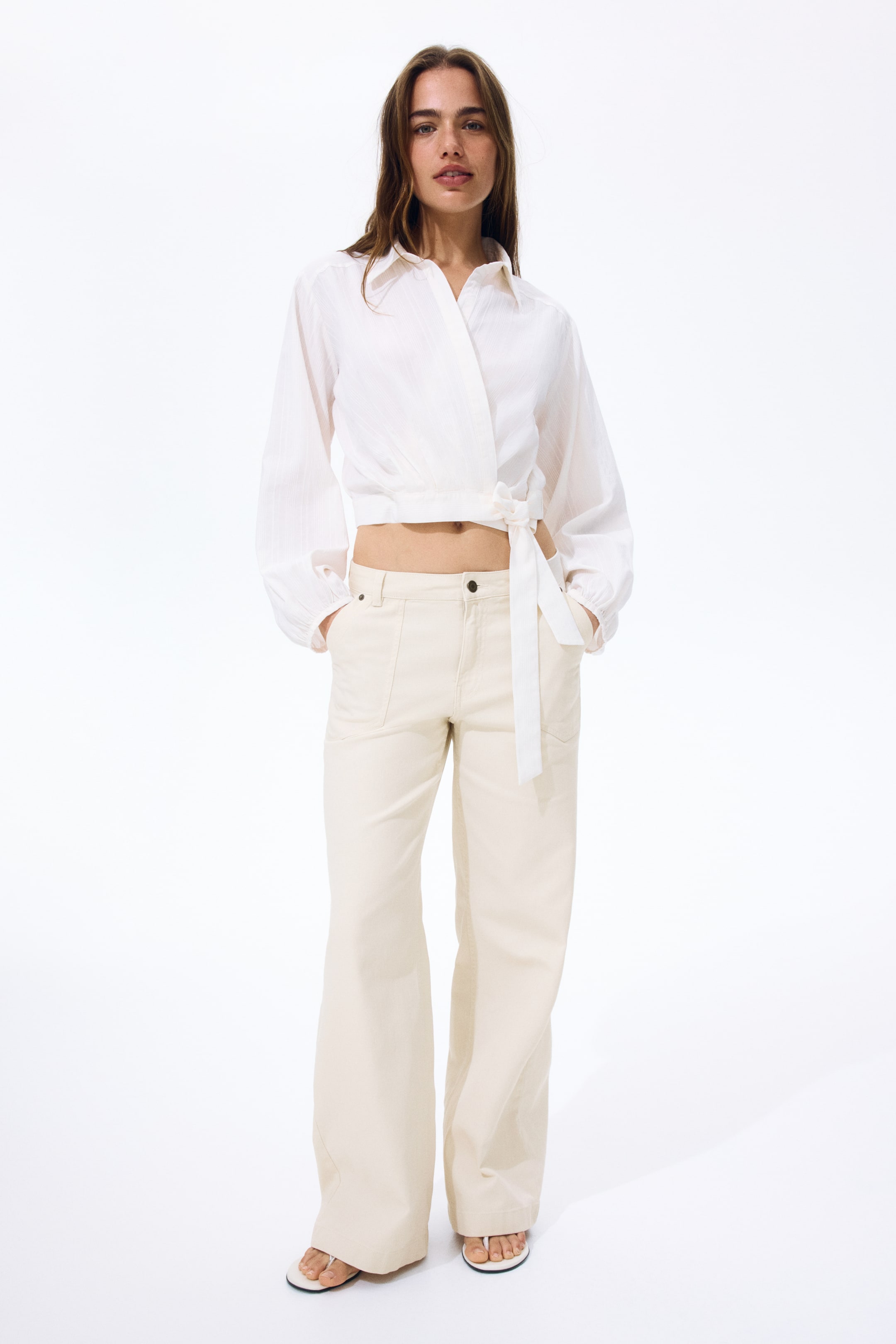 View larger image: Light beige cotton twill trousers feature a high waist with a zip fly and button closure at the front, along with patch side pockets and wide legs.