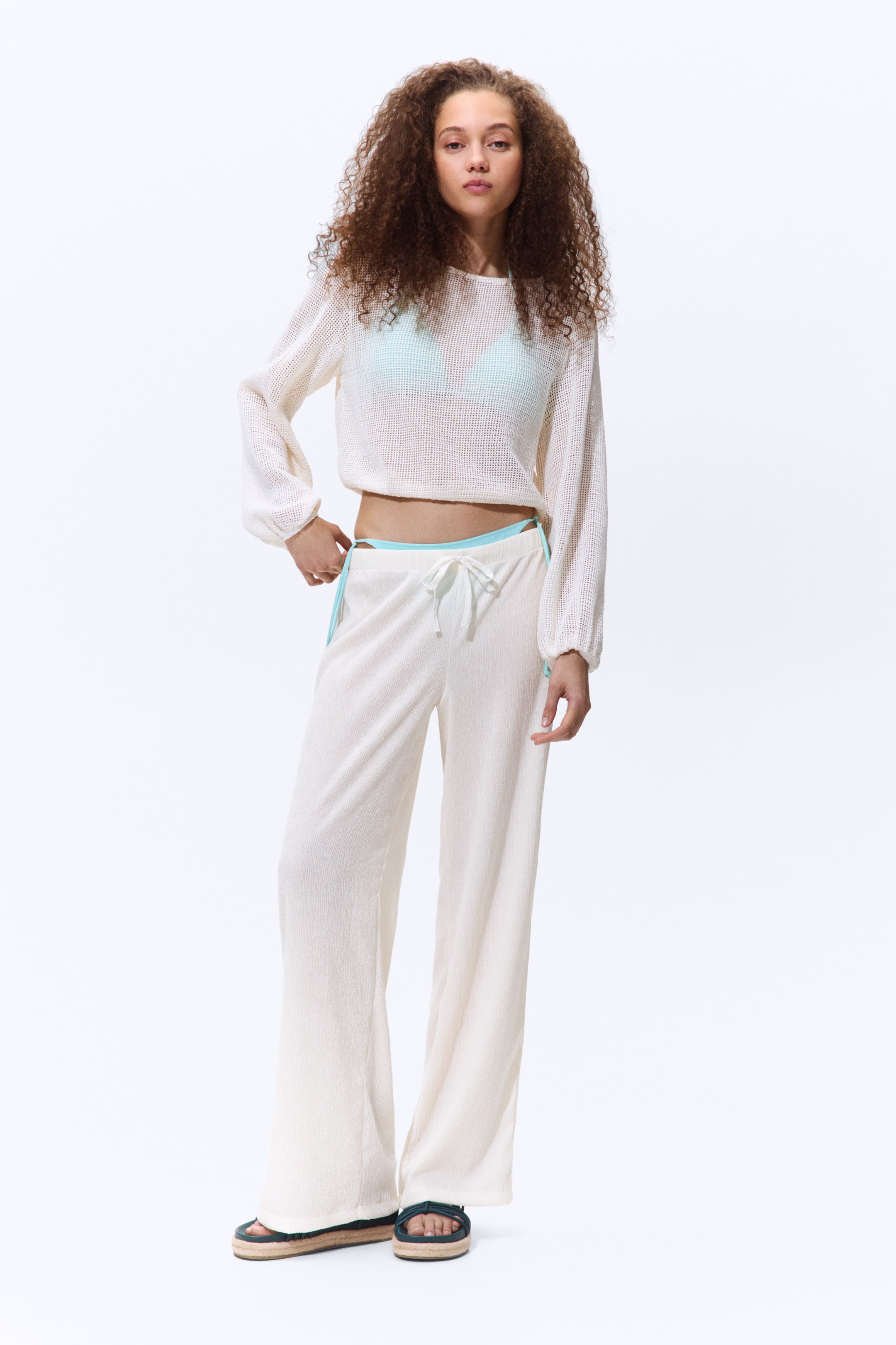 Größeres Bild ansehen: Die Hose aus geknittertem Jersey mit elastischem Bund und Kordelzug sowie geraden Beinen wird vom Model getragen. Ein hellblaues Bikinihöschen ist oberhalb des Hosenbunds sichtbar.