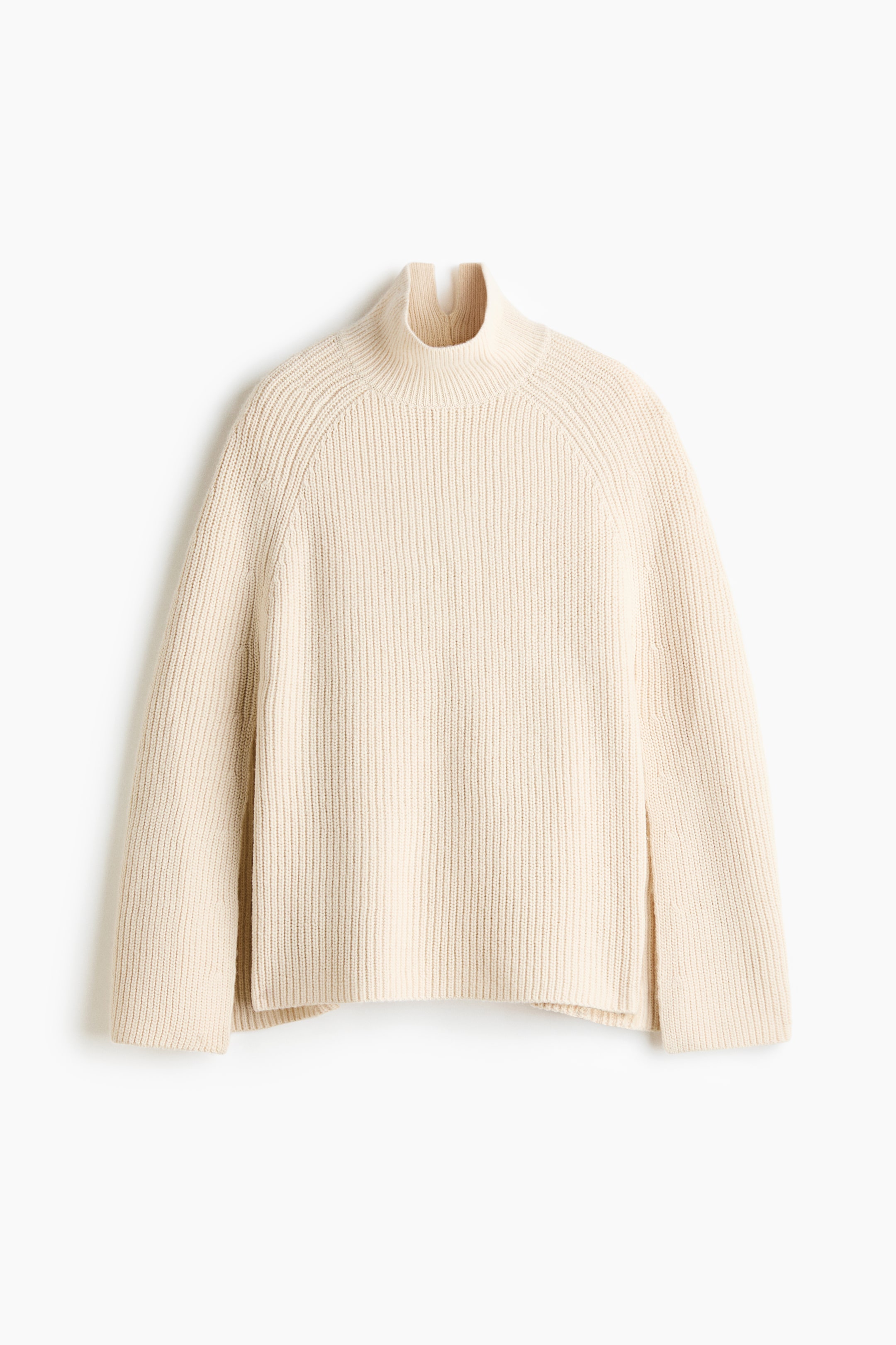 View larger image: A cream ribbed knit sweater is shown from the front. It features a split mock neck, raglan sleeves, and side slits at the hem.