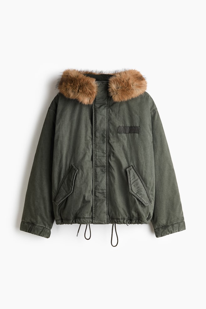 This Padded Twill Parka in dark olive green is displaying a front-facing view, featuring a hood with a plush, brown faux-fur trim. The parka is showcasing a concealed front zip closure, two angled front pockets with flaps, and an adjustable elasticized hem with hanging drawstrings. - 1