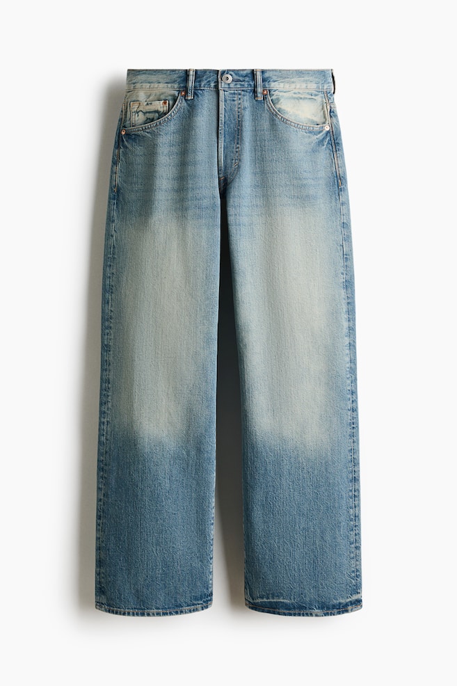Phần trước của chiếc quần jean denim màu xanh nhạt này có dáng rộng, thoải mái, xuất hiện với phần đùi được giặt phai màu và tông màu đậm hơn ở phần chân dưới. Chúng có cạp vừa, khóa nút, dây kéo và túi trước cong có túi đựng tiền xu. - 1