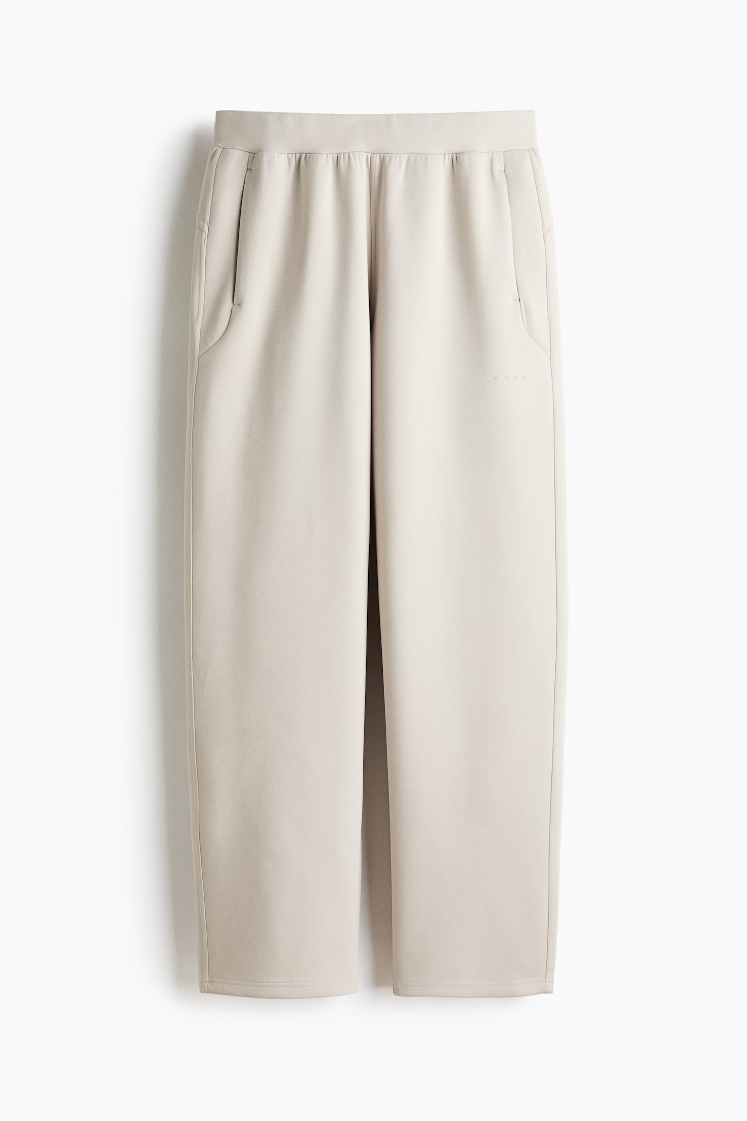 A pair of light beige pants is presenting with an elasticated waistband and two curved-opening side pockets. Vertical seams are running down the front of each straight-cut leg, which is ending in a plain stitched hem, and a subtle 'NOVE' logo is debossed on the upper right thigh. - 1
