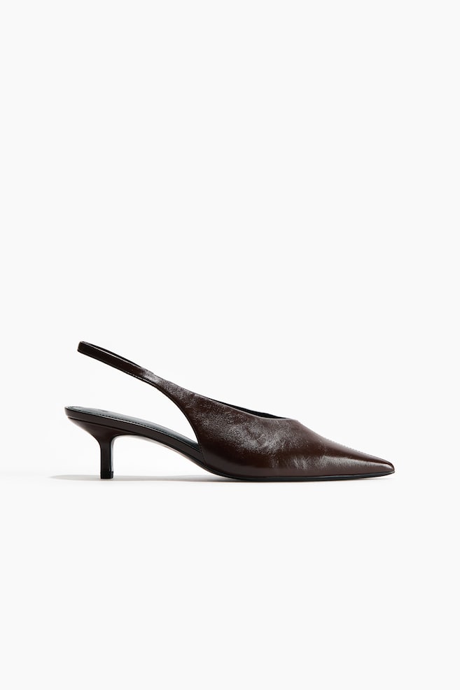 A dark brown leather slingback pump is displaying its side profile, featuring a pointed toe, a slender kitten heel, and a thin slingback strap. - 1