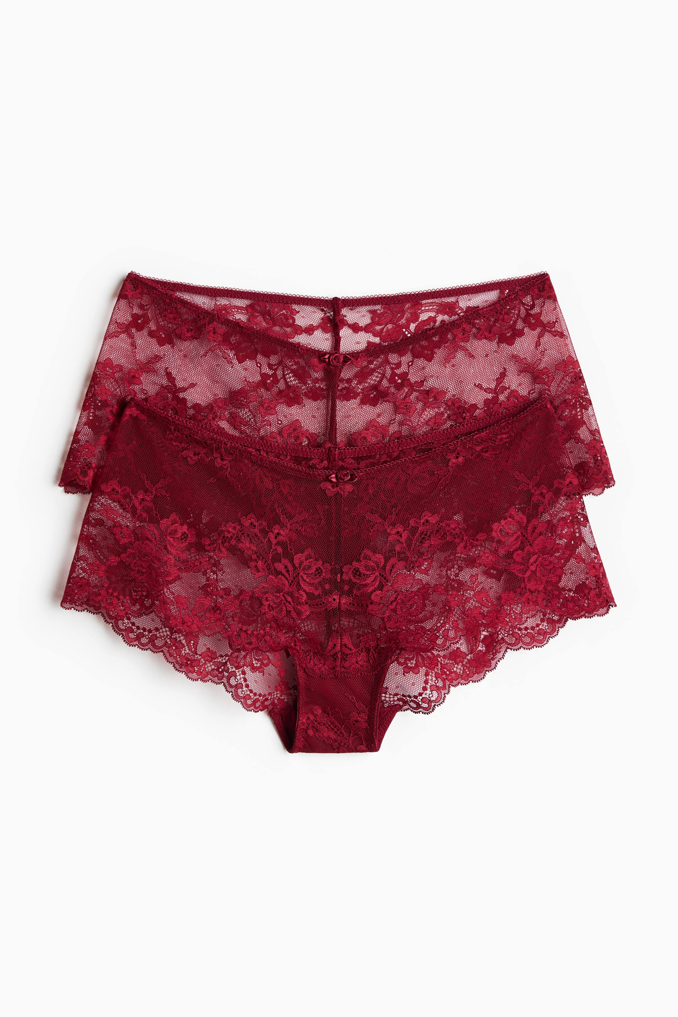 View larger image: Two pairs of dark red lace underwear are lying flat, stacked one slightly behind the other and facing front. The underwear feature a sheer floral lace design with scalloped trim along the edges and a small decorative bow at the centre of the waistband.