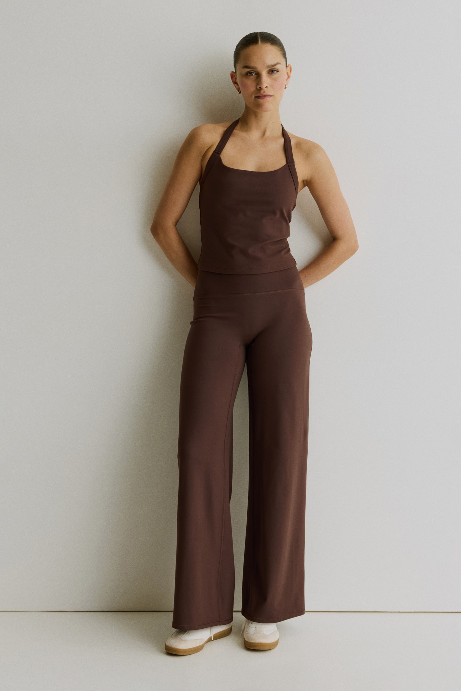 Wide brown sports trousers are laid flat, front-facing, showcasing a high-rise, wide waistband and wide legs with a smooth fabric texture and straight hems. - 1