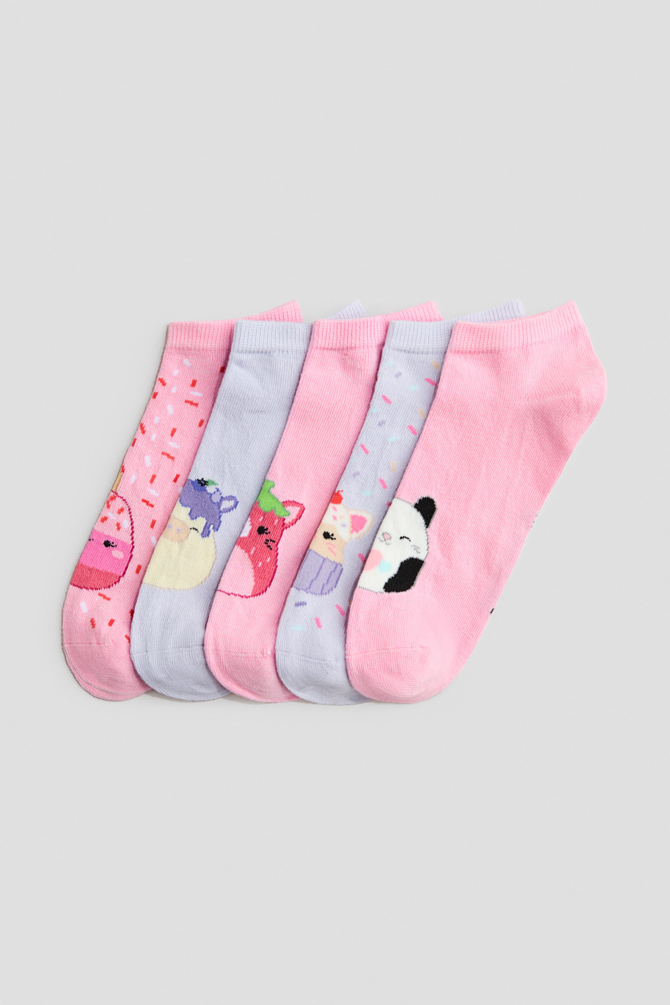 Agrandir l'image: Cinq chaussettes sans tige présentent leurs devants, disposées en éventail. Elles arborent des motifs en maille fine dans des tons roses et violet clair, avec des motifs incluant des éclats, une glace fondante, des personnages animaliers et des cupcakes. Chaque chaussette montre un haut élastiqué.
