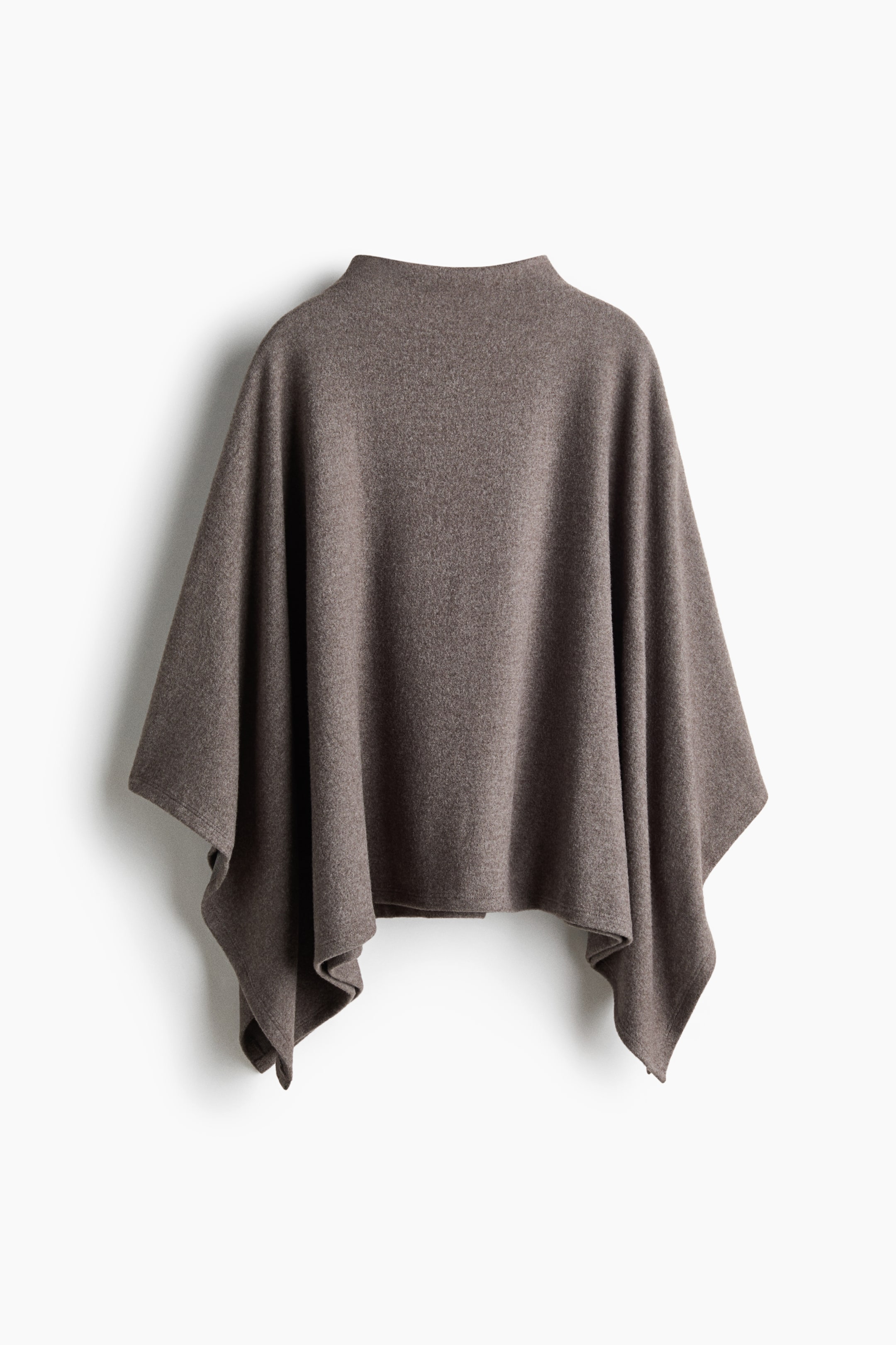 Voir une image plus grande: Un poncho tricoté brun taupe est suspendu de face, mettant en valeur sa silhouette ample et drapée. Le vêtement présente un col montant style faux col et de larges côtés ouverts qui retombent en plis doux et asymétriques.