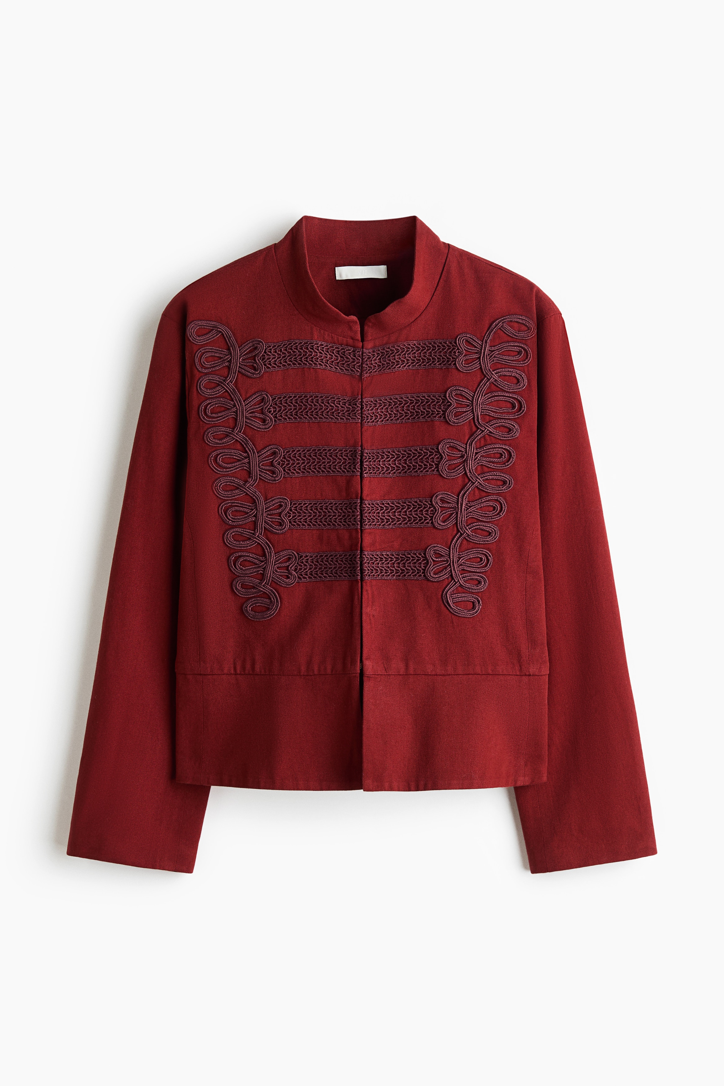 A dark red, military-inspired jacket is shown from the front, displaying intricate braided cord embroidery across the chest. The jacket features a band collar, long straight sleeves, and a concealed front closure.